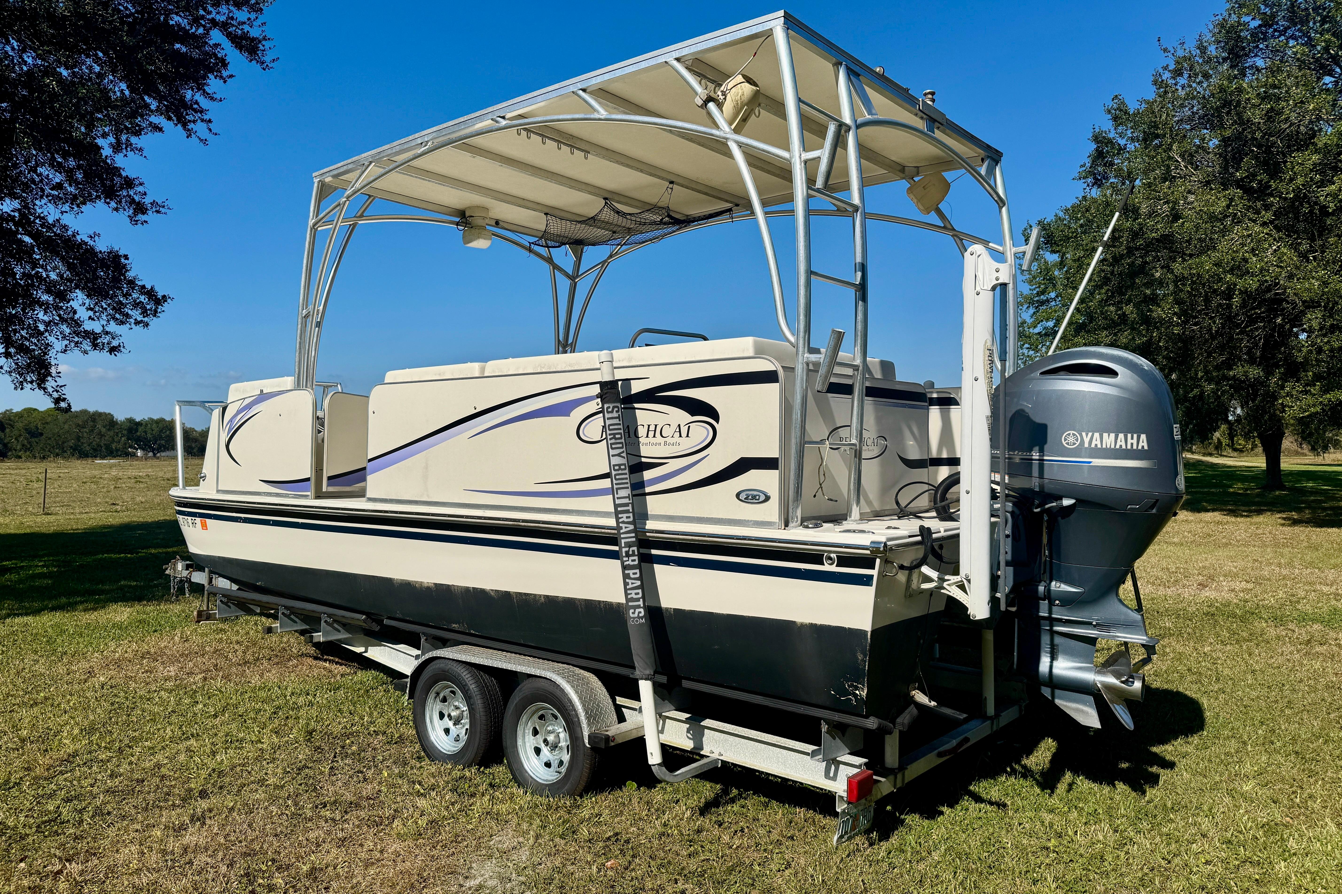 2017 Beachcat 230 boat on trailer with Yamaha outboard motor, parked on grass.