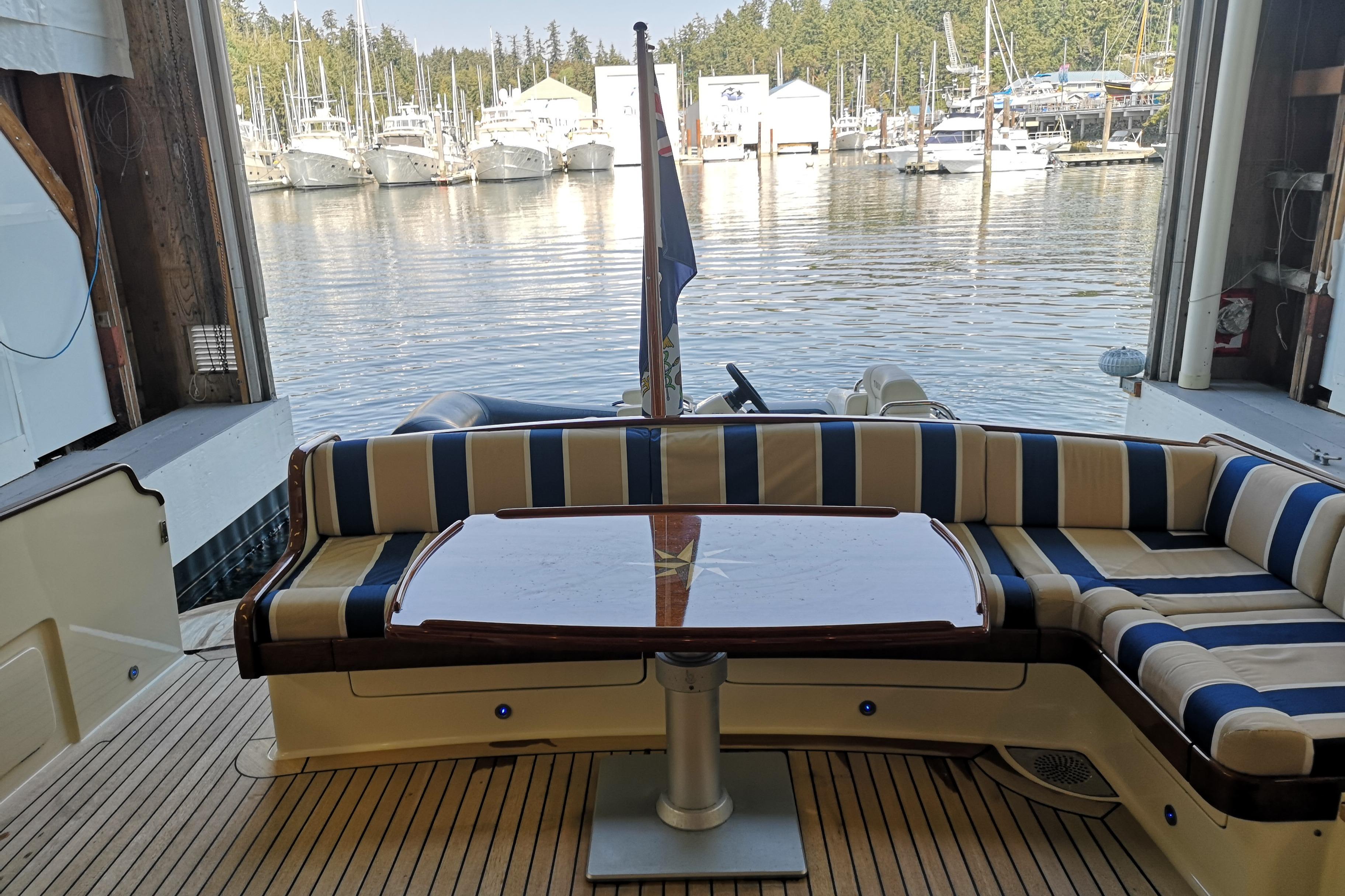2006 Vicem 54 Classic yacht interior with striped seating and wooden table, docked at a marina.