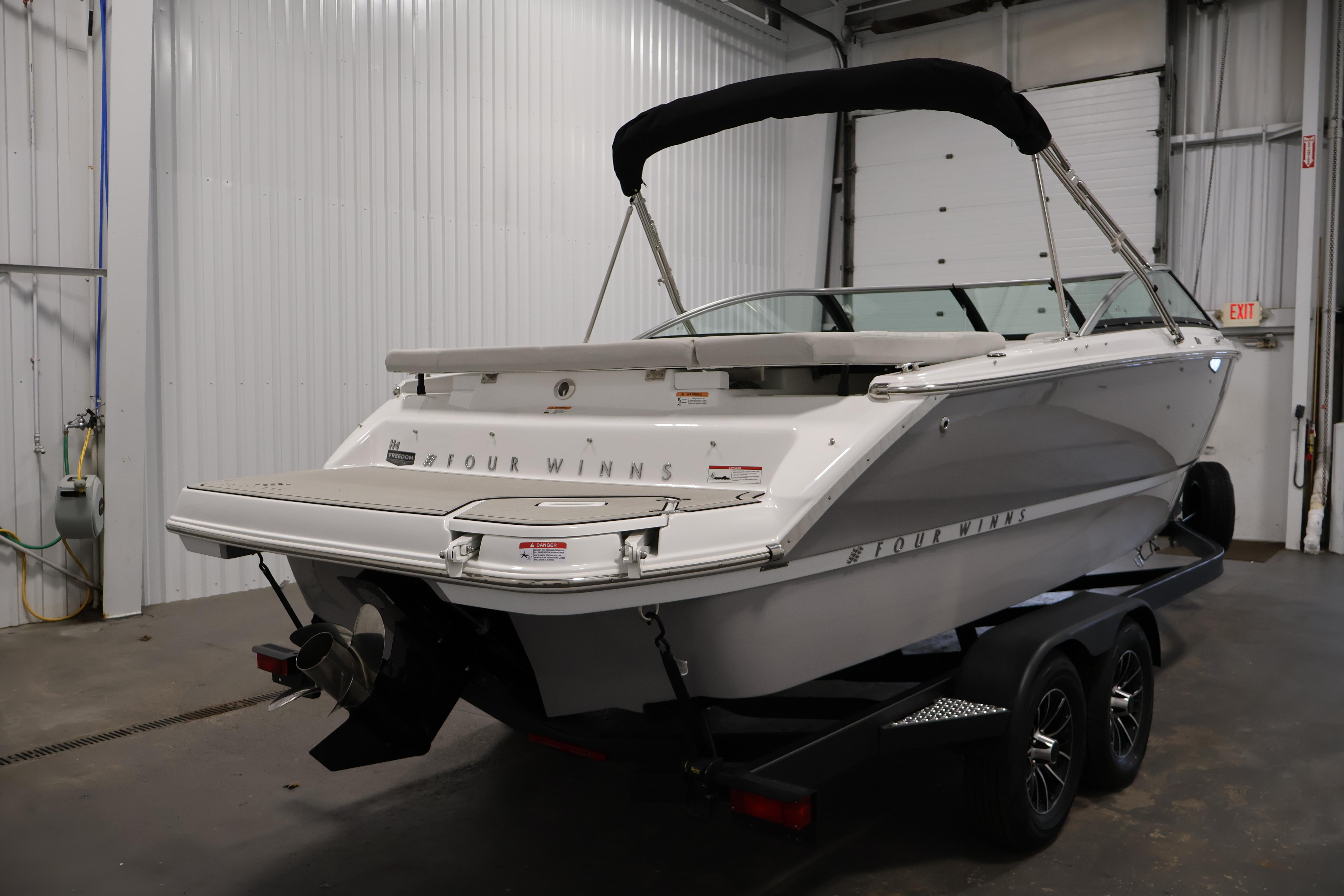 2026 Four Winns H4 Freedom boat in a garage, rear view on trailer.