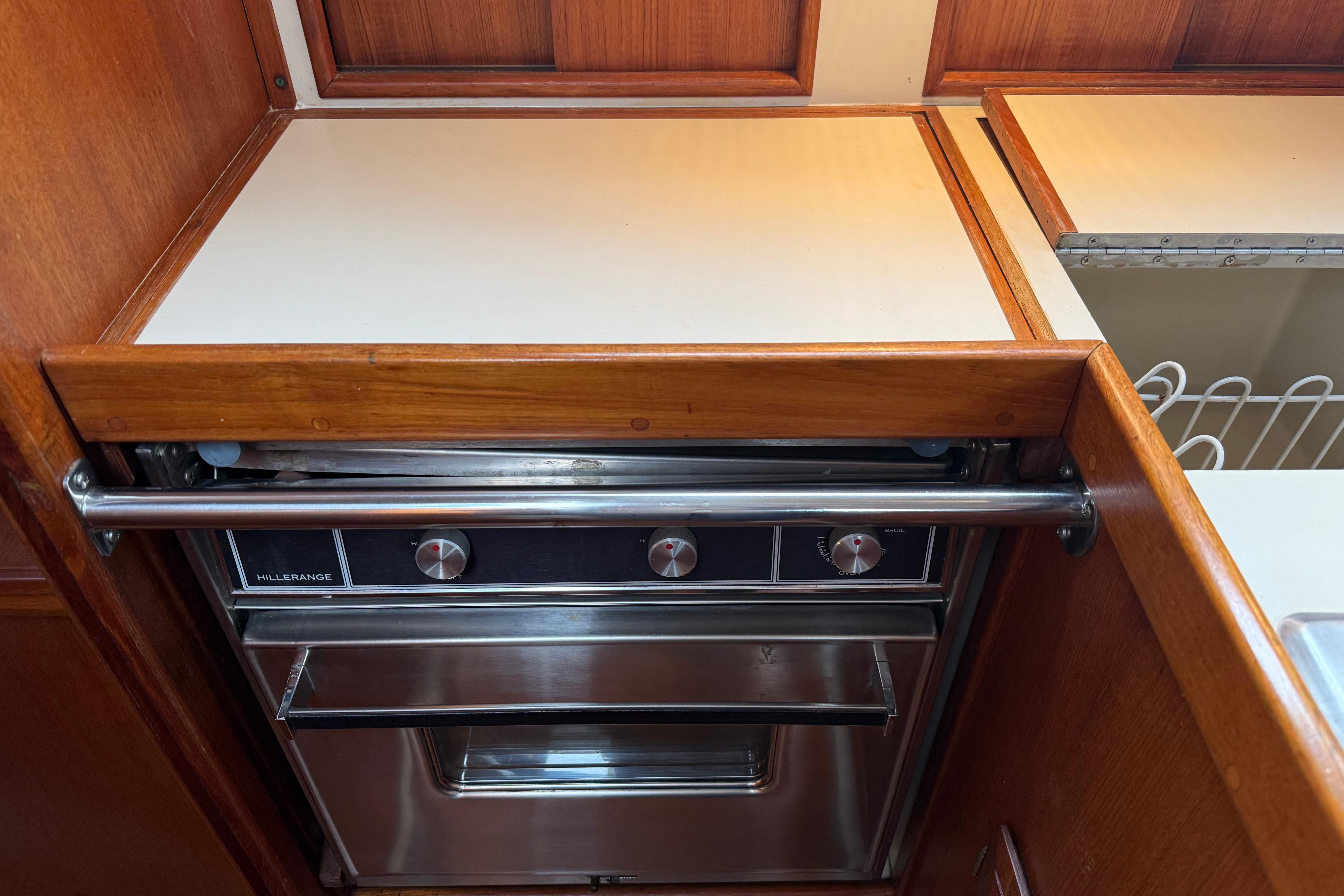 Ericson 32-200 (1988) yacht kitchen with Hillerange stove and wooden cabinetry.