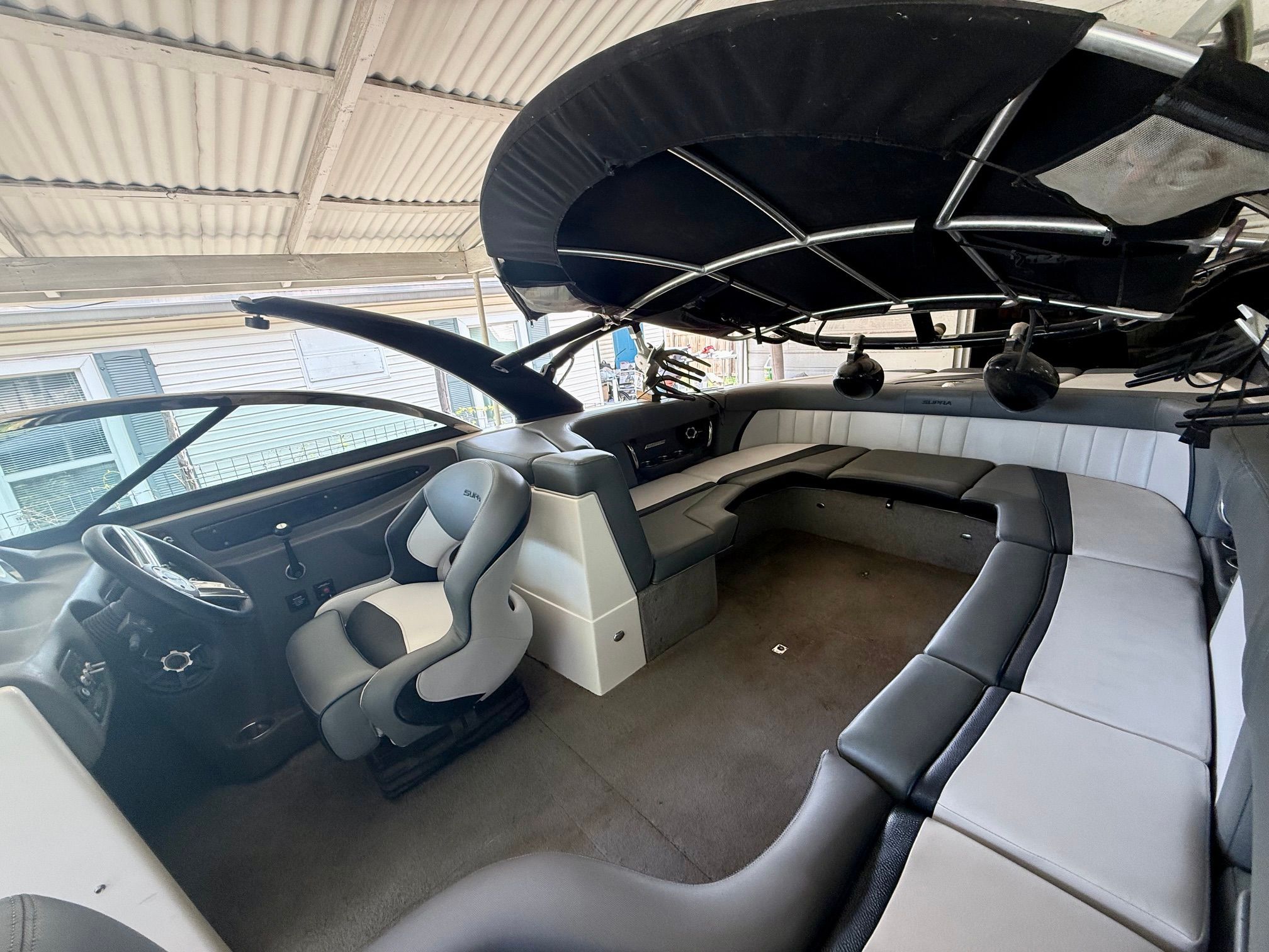 Interior of a 2012 Supra Launch 242 with gray and black seating under a black canopy.