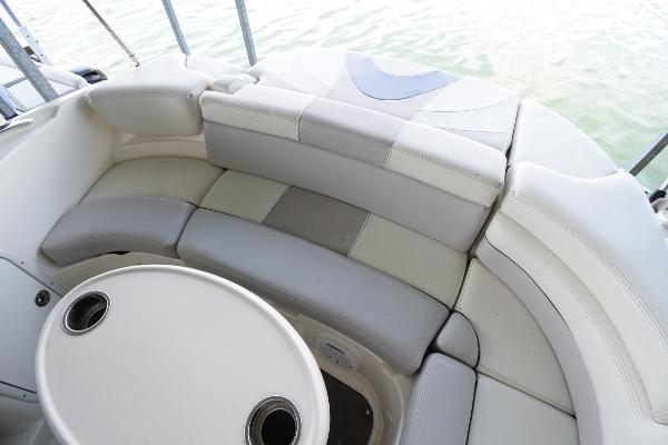 The image shows a white and gray curved seating area on a boat with a table in the center.