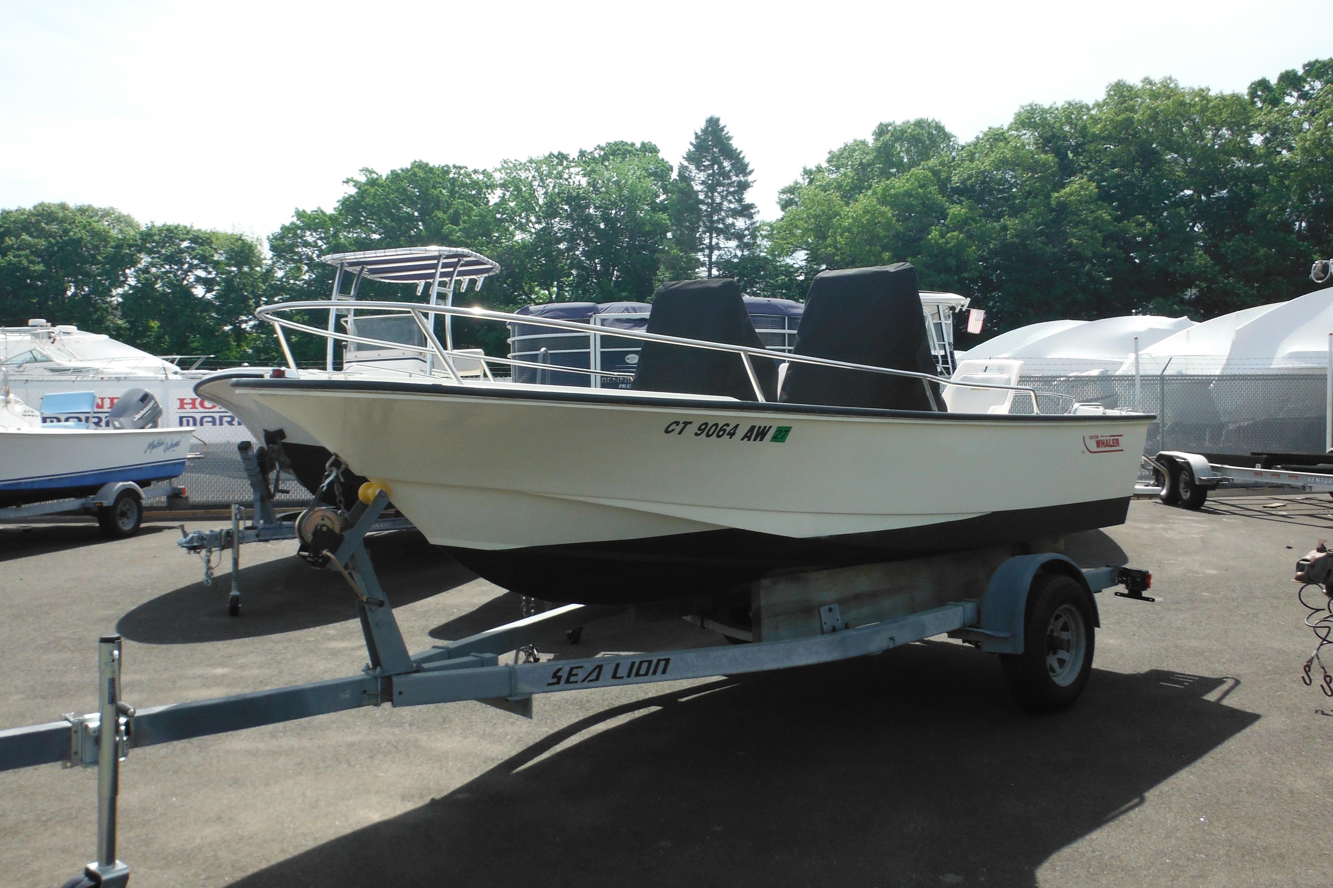 1991 Boston Whaler 16 SL boat on trailer, parked outdoors with trees in background.