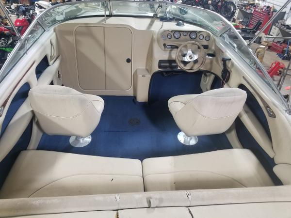 Interior of a 1999 Custom 190 boat with beige seats and blue carpet.