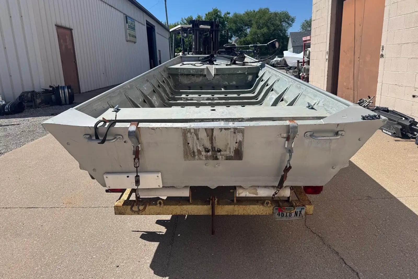 1973 Monark 14 Jon boat on trailer, parked outside industrial building.