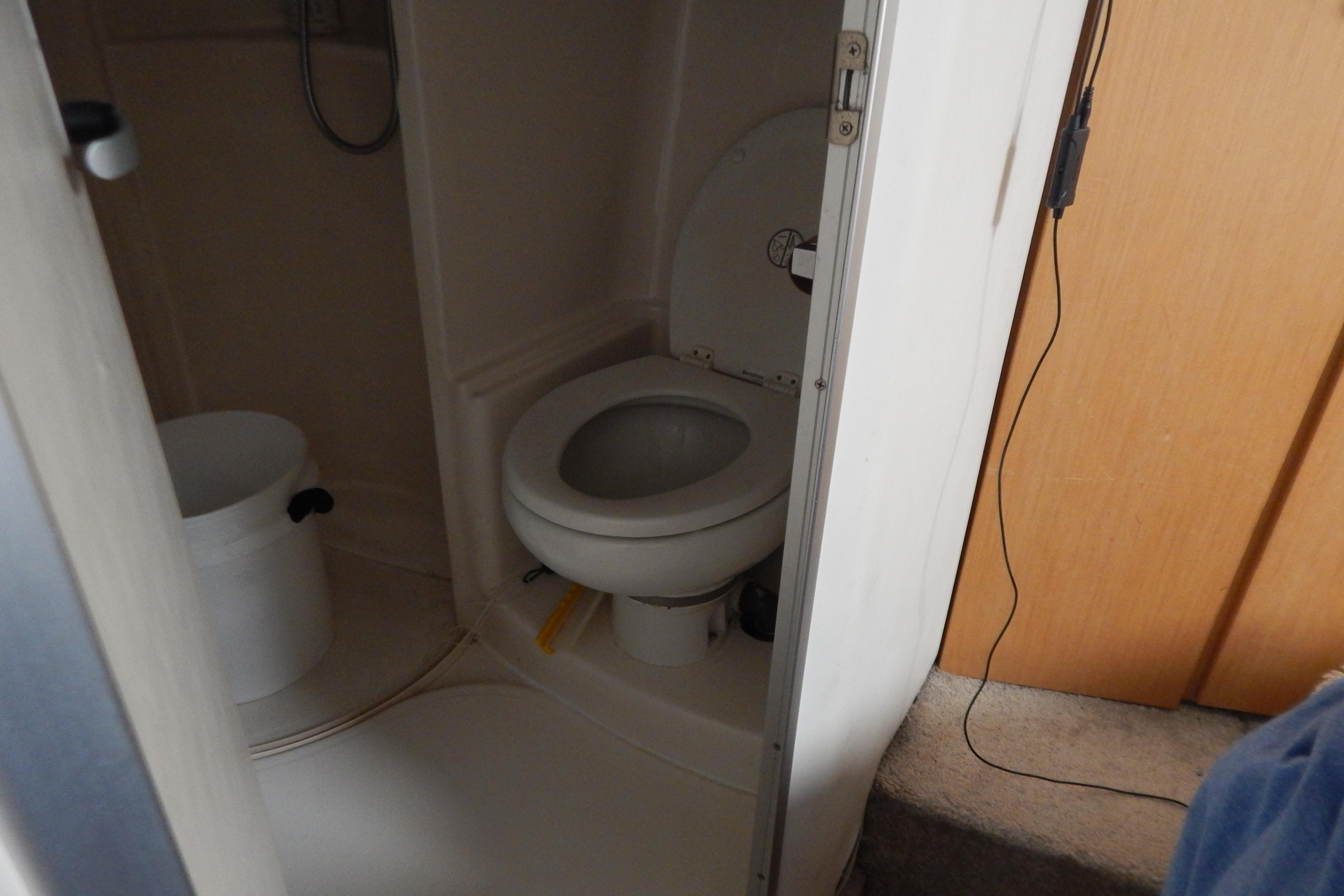 Compact bathroom in a 1998 Magnum 4100 SCR boat, featuring a toilet and shower area.