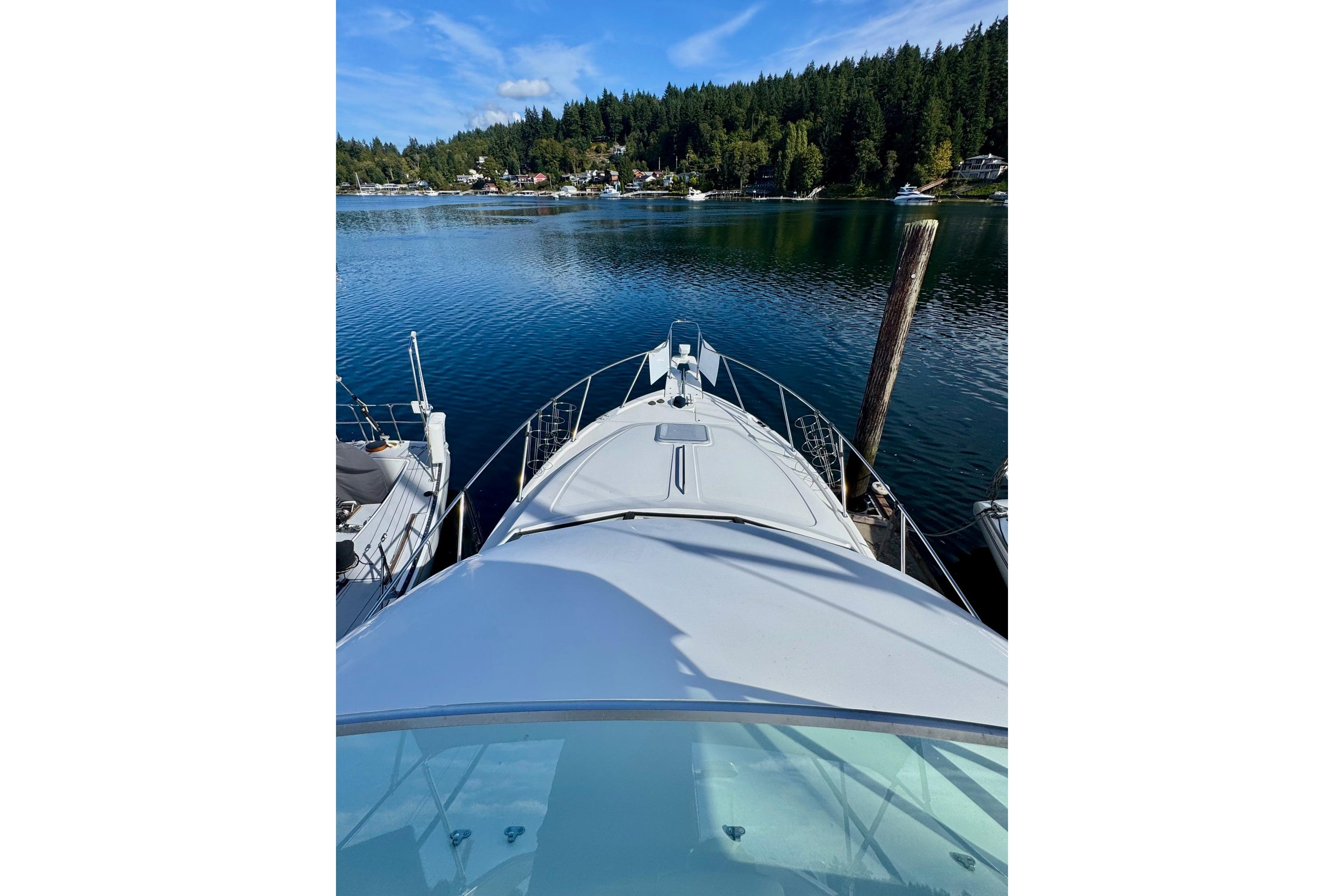 1998 Bayliner 3388 Command Bridge Motoryacht docked on serene lake with forested shoreline.