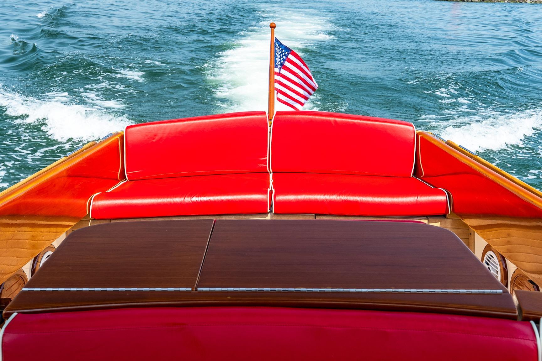 2005 Hinckley Talaria 29R with red seating and American flag on open water.