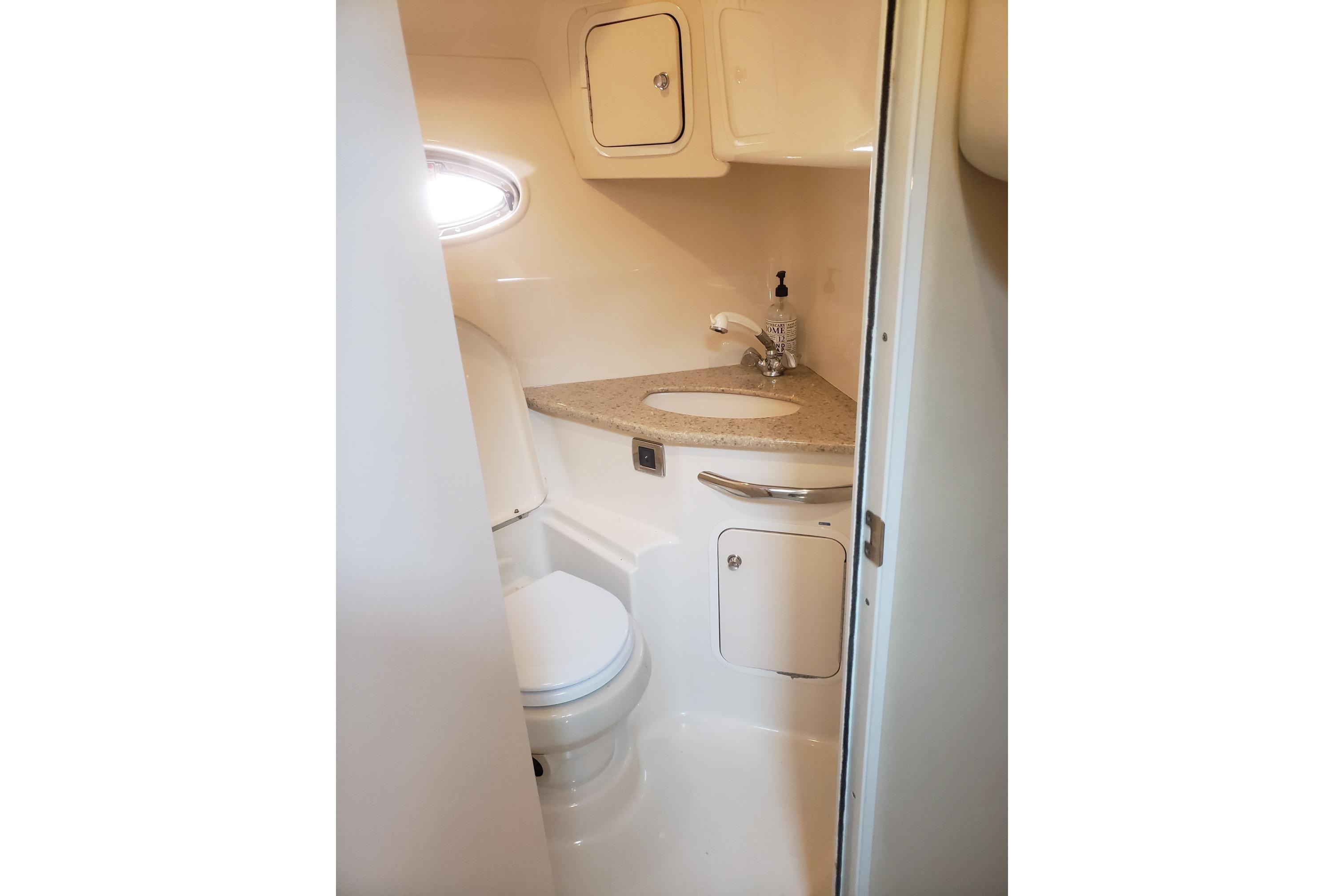 2003 Sea Ray 420 Sundancer bathroom with sink, toilet, and storage cabinets.