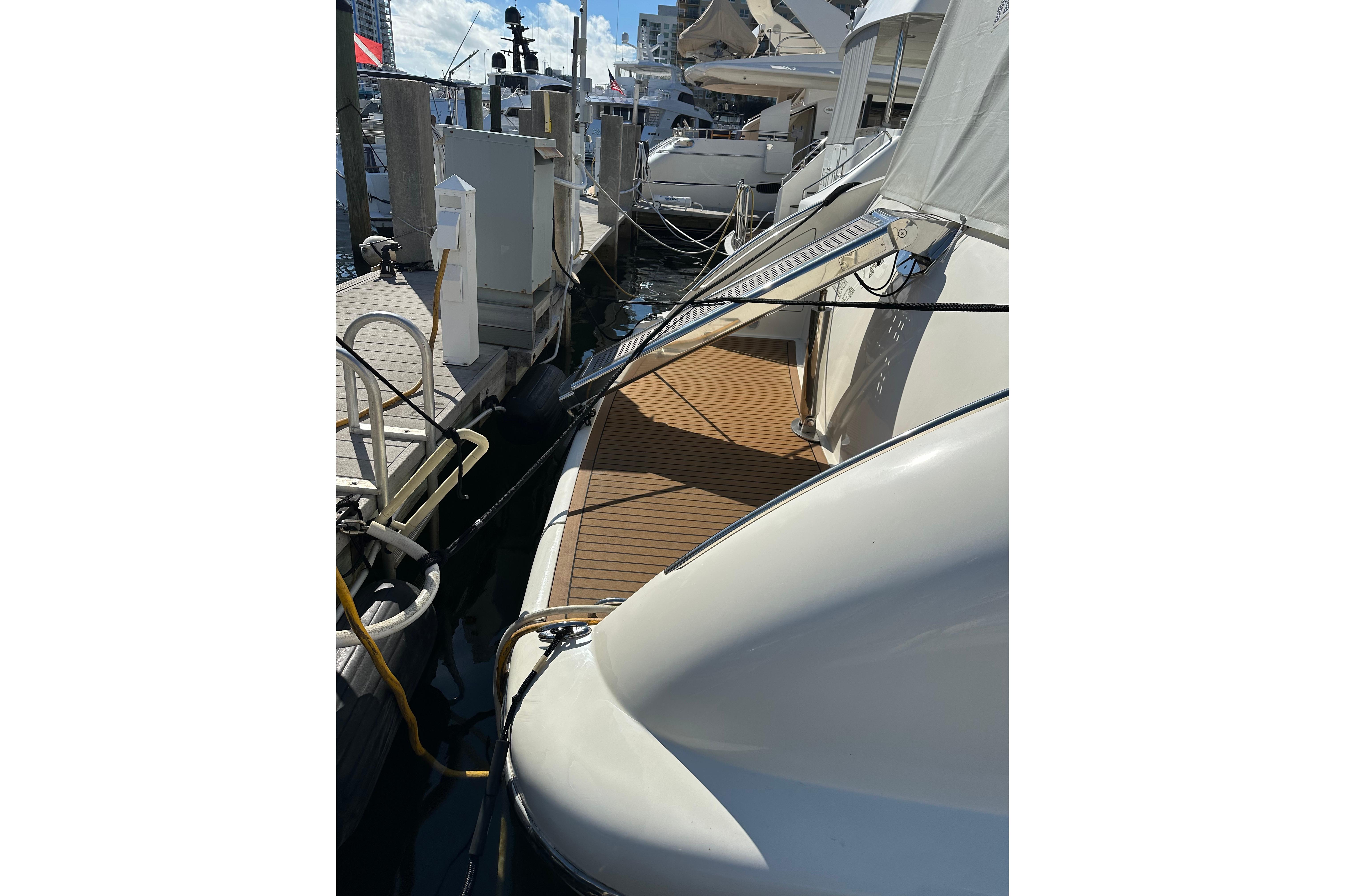 2004 Azimut 55E yacht docked at marina with wooden deck and gangway.