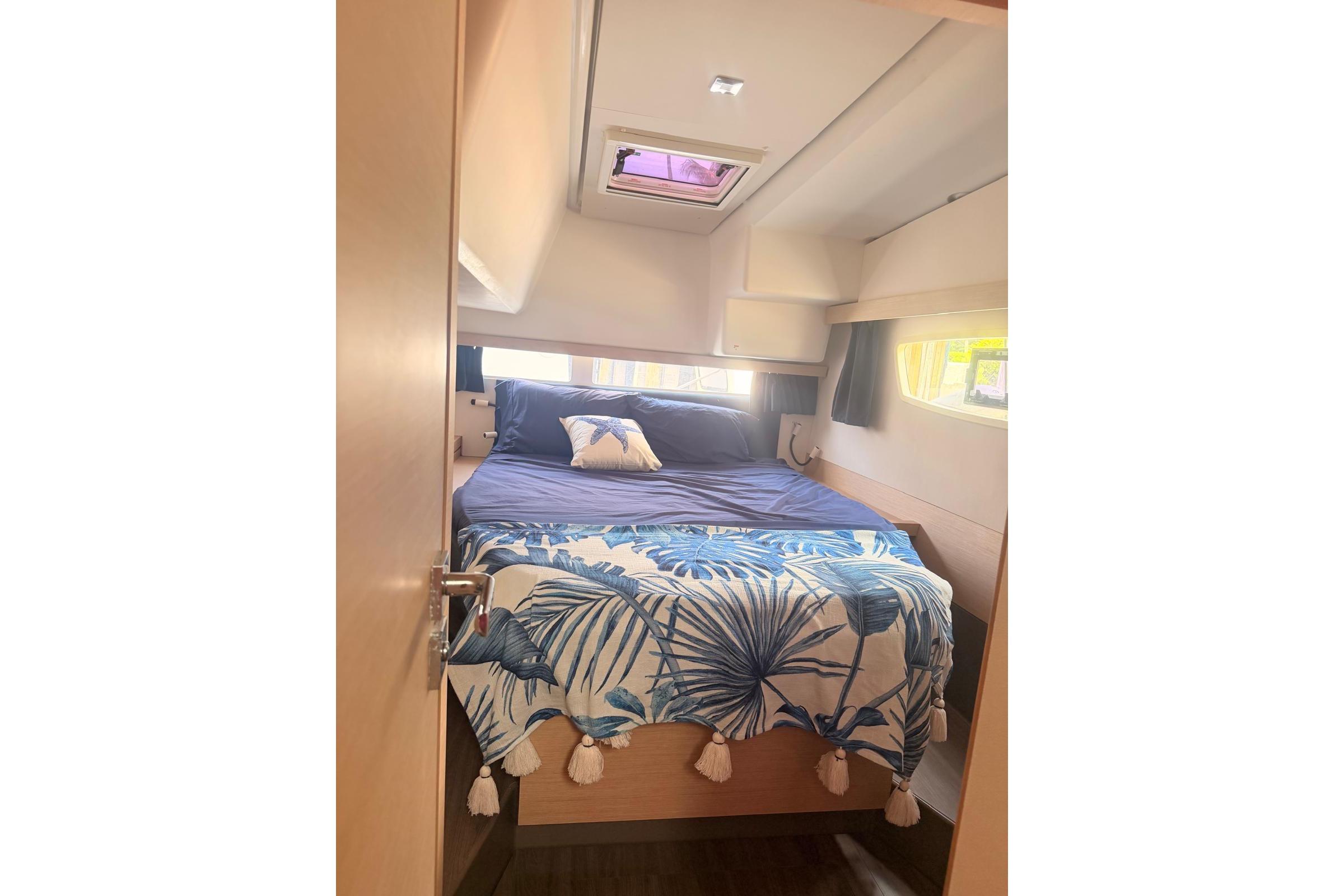 Cozy cabin interior of 2018 Fountaine Pajot Lucia 40 with nautical-themed bedding.
