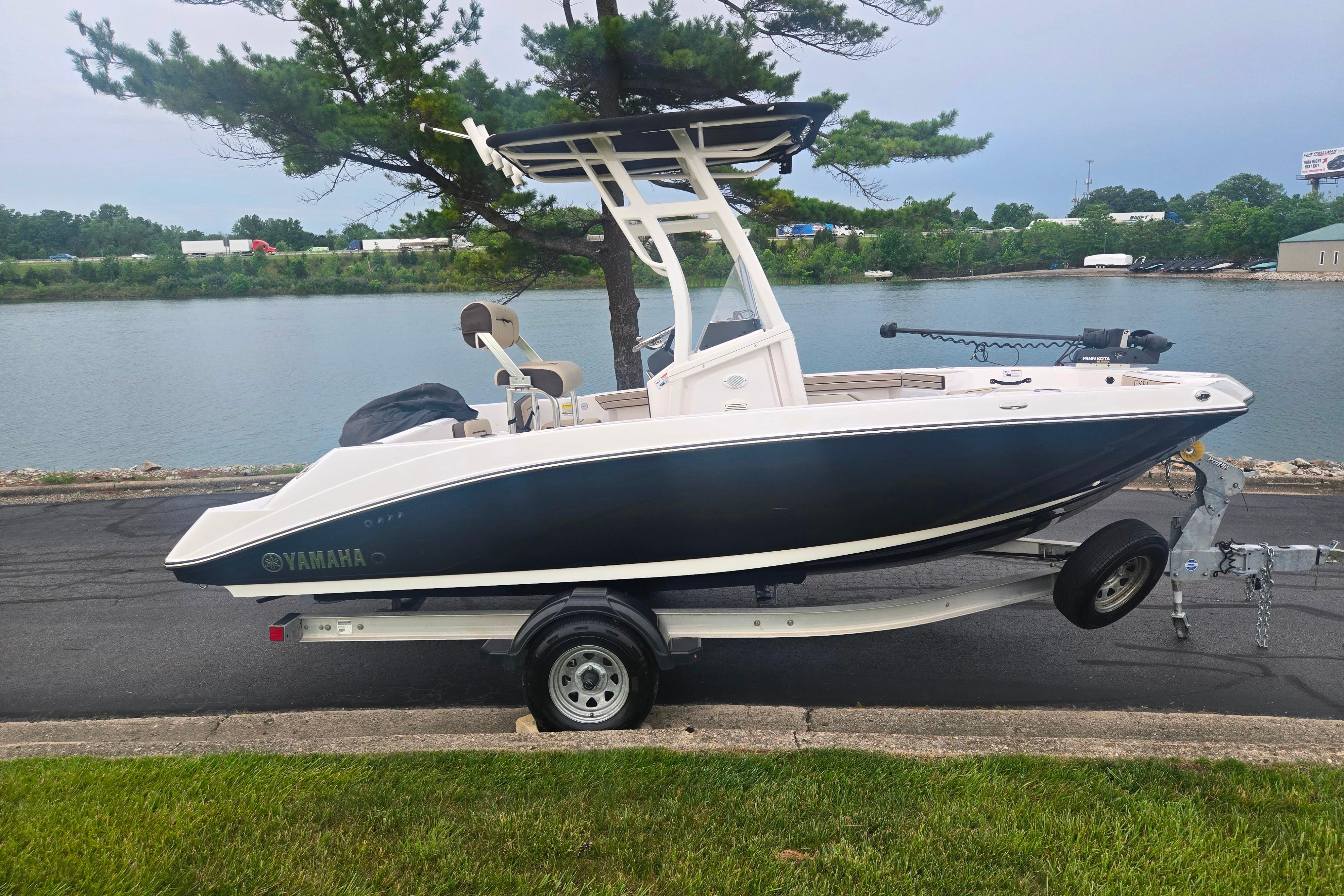 2022 Yamaha Boats 195 FSH Sport on trailer by a lakeside road.