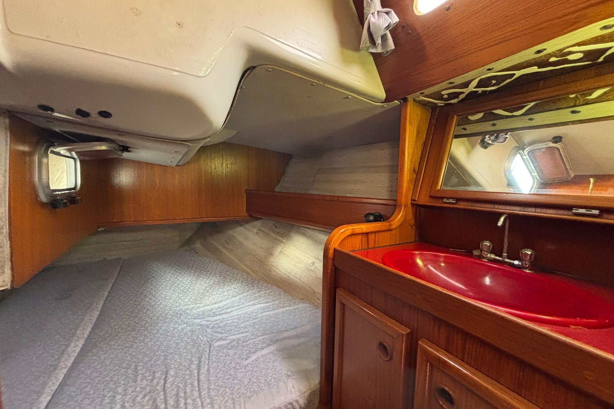 Interior cabin of 1986 Jeanneau Sun Shine 38 sailboat with bed and red sink.