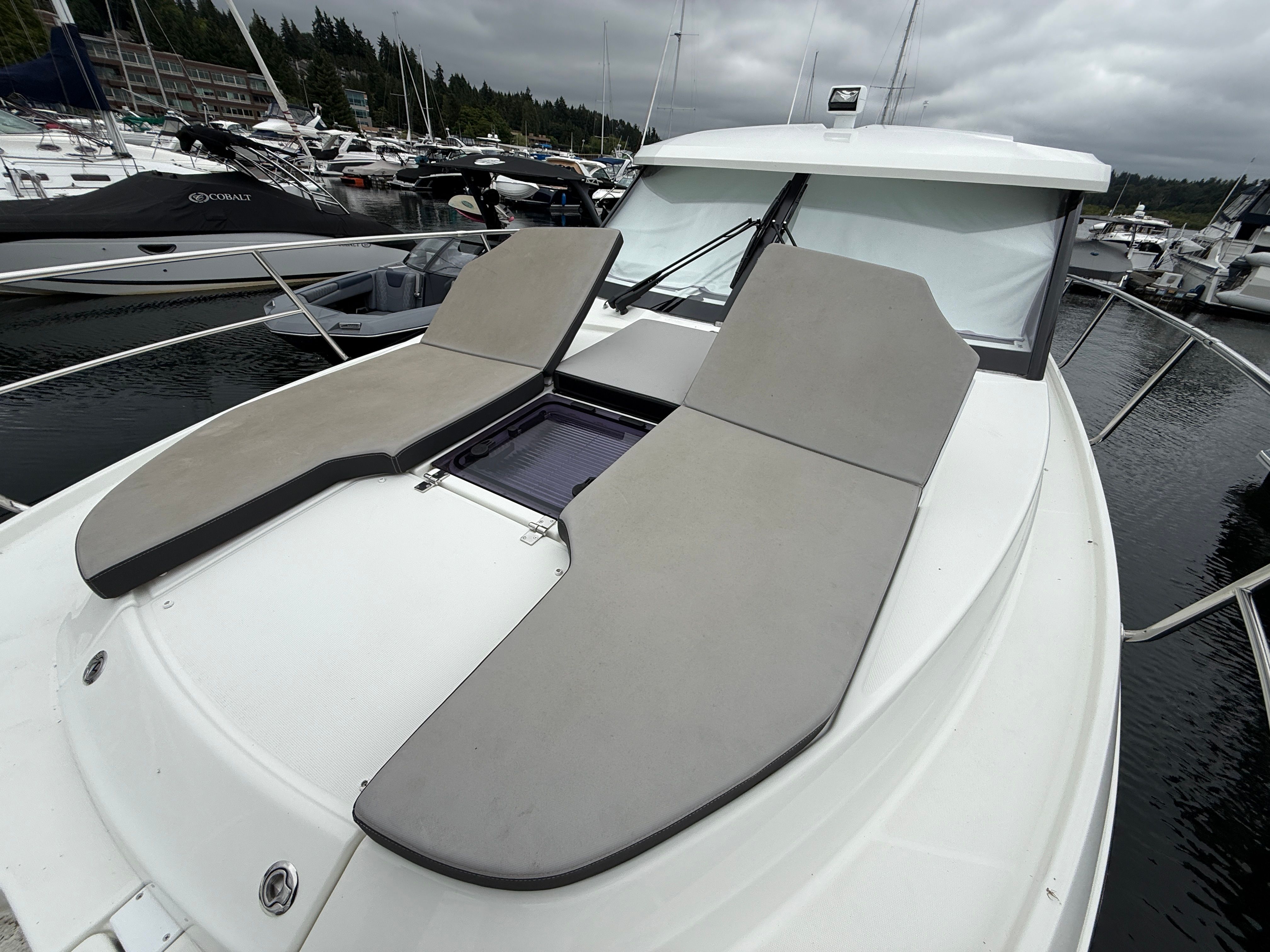 The boat features two cushioned sun pads on the deck, docked in a marina.