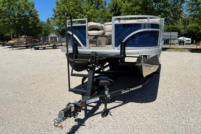 2025 Sun Tracker Fishin' Barge 22 DLX pontoon boat on trailer in sunny outdoor setting.