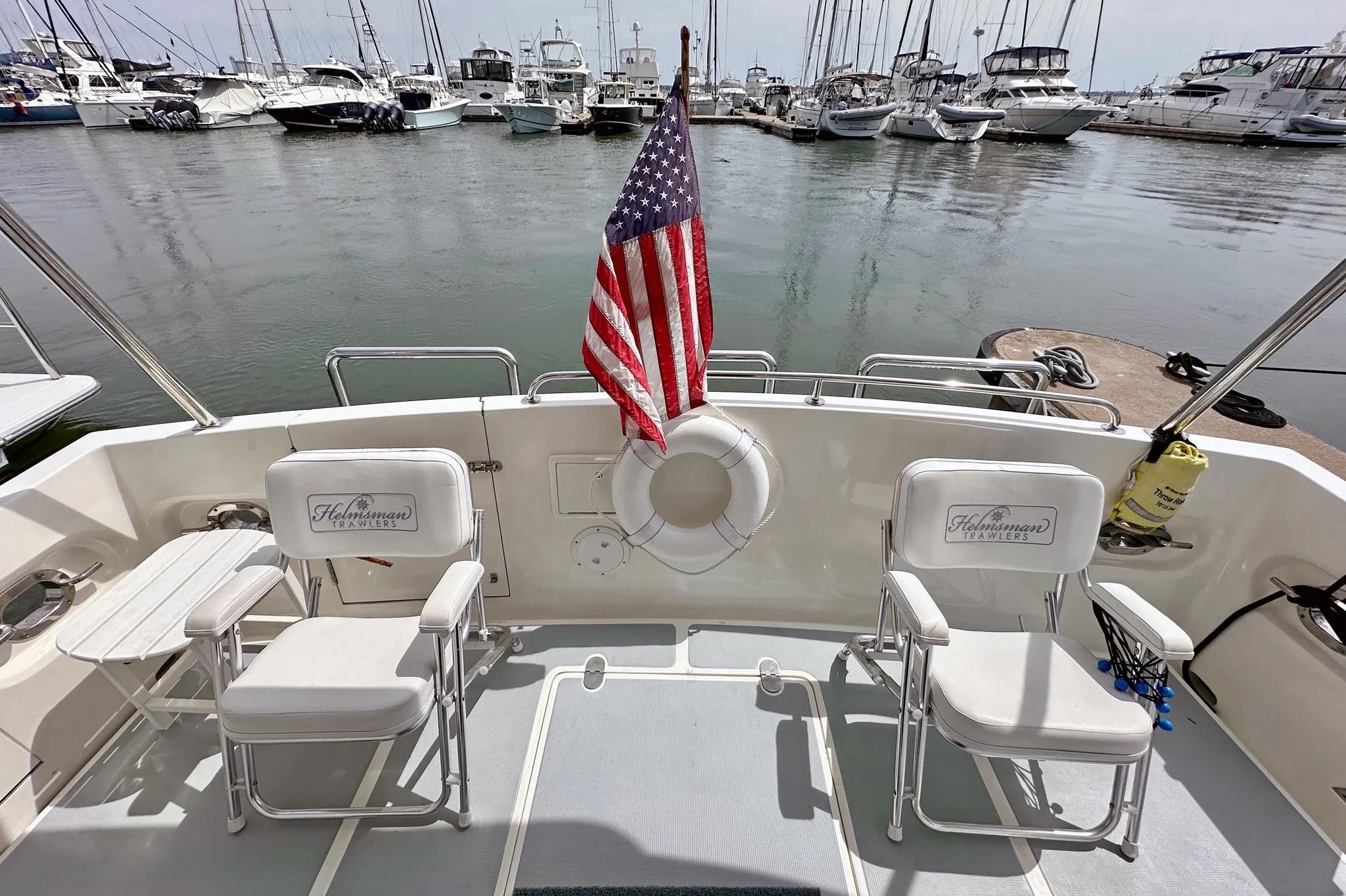 2016 Helmsman Trawlers 38 Pilothouse boat deck with chairs and American flag.