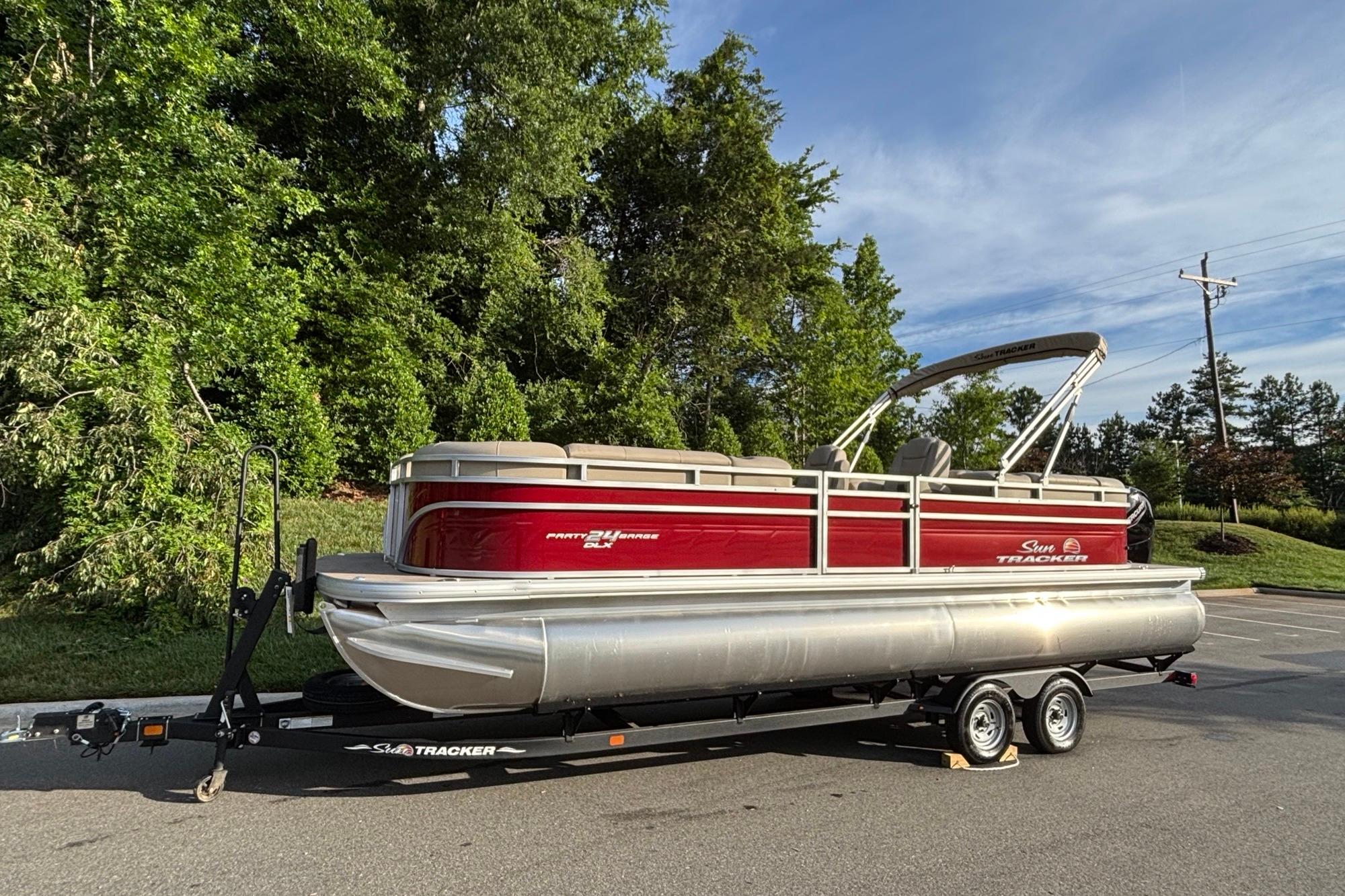 2025 Sun Tracker Party Barge 24 DLX pontoon boat on trailer, parked outdoors.
