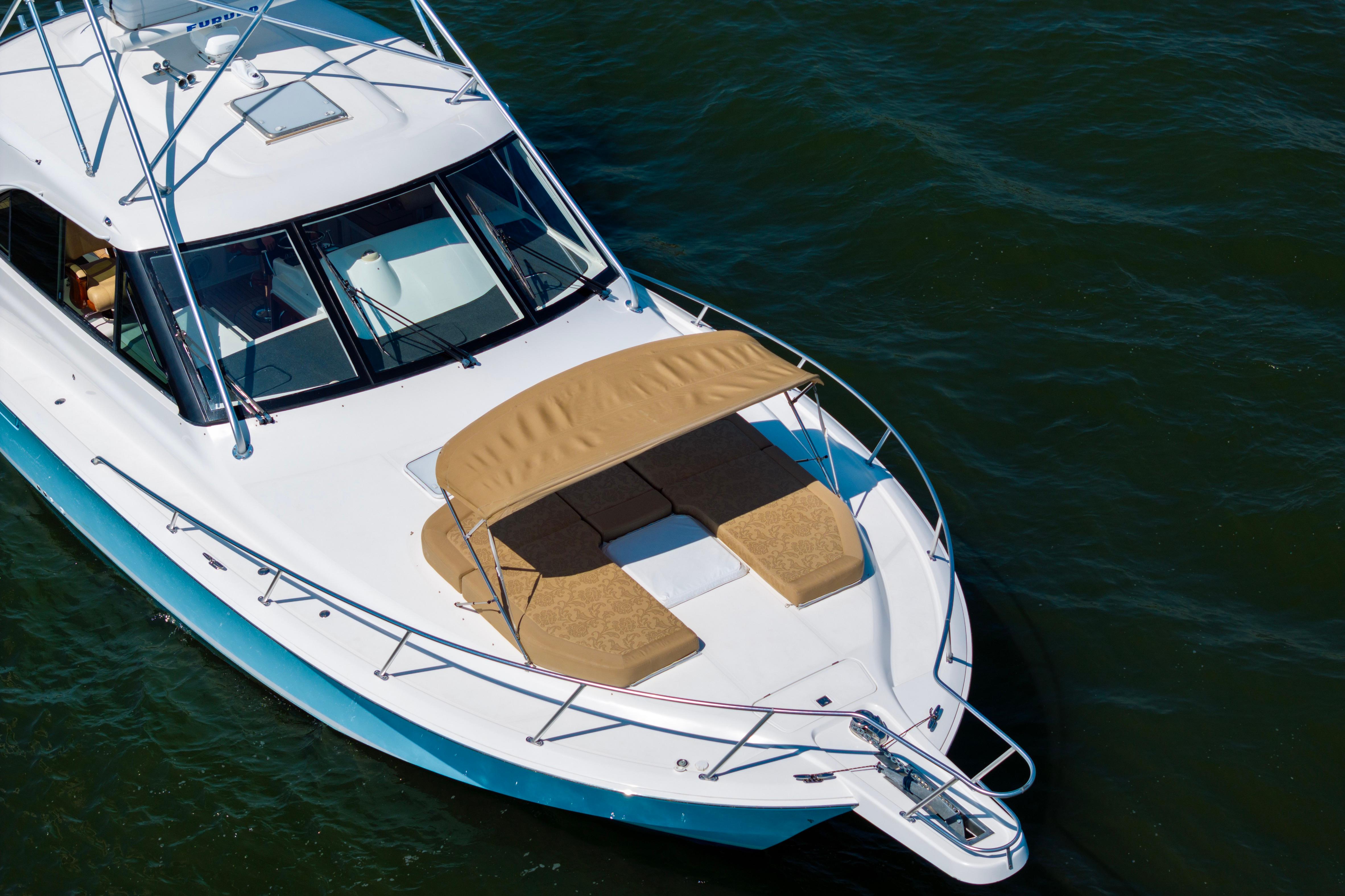 2012 Cabo 44 Hardtop Express yacht with sunbathing area on calm water.