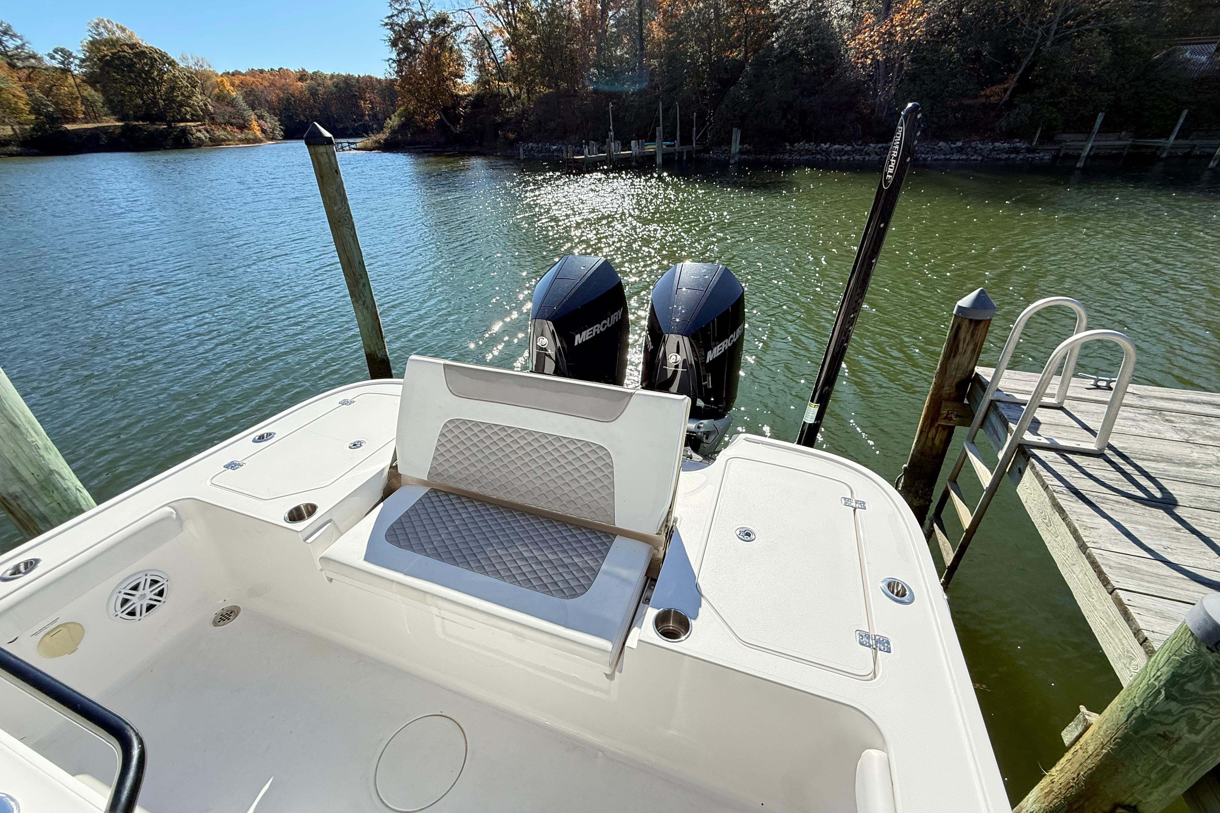 2023 Caymas 281 HB boat with dual Mercury engines docked by a serene lake.