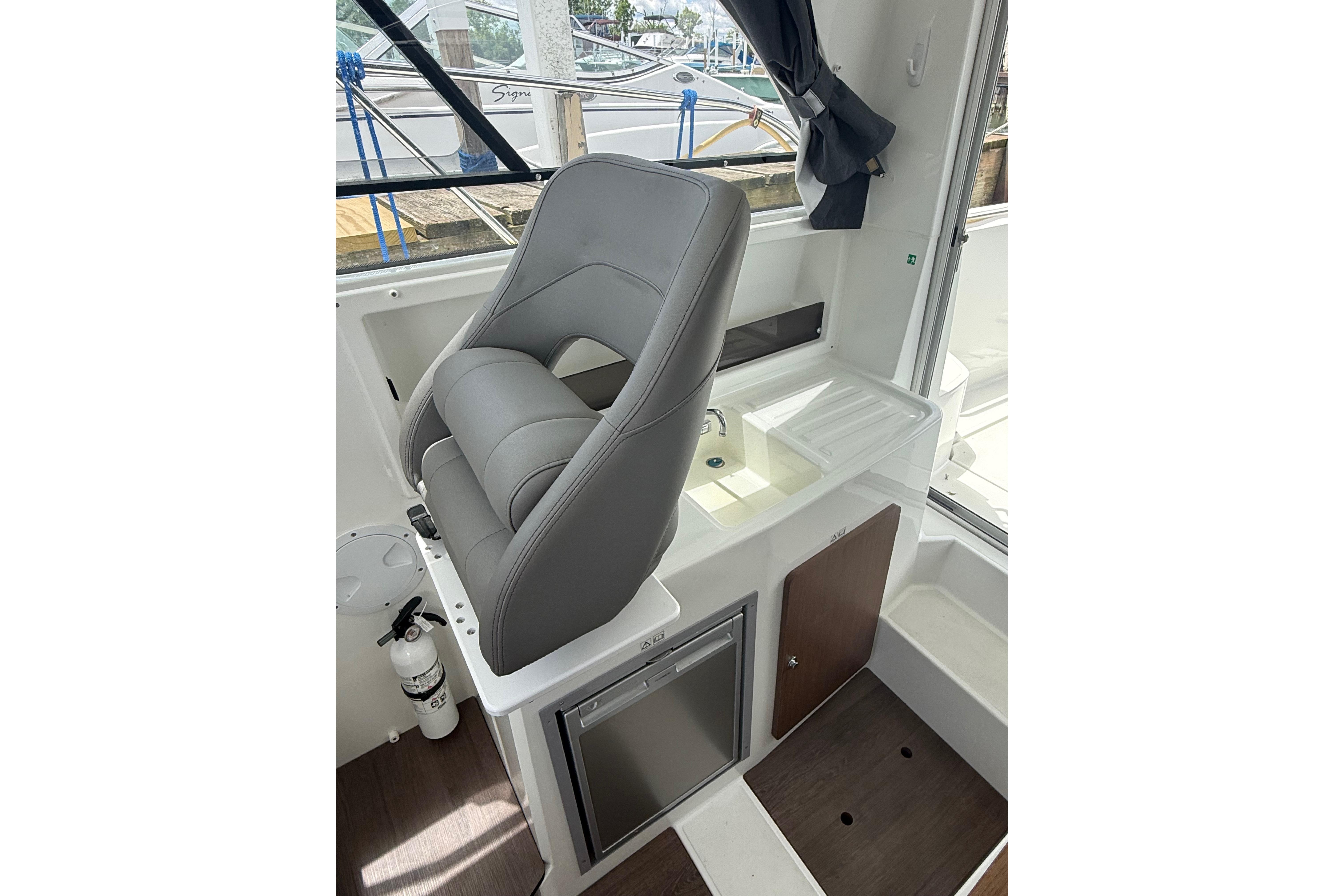 Interior of 2019 Beneteau Antares 23 boat with helm seat and kitchenette.