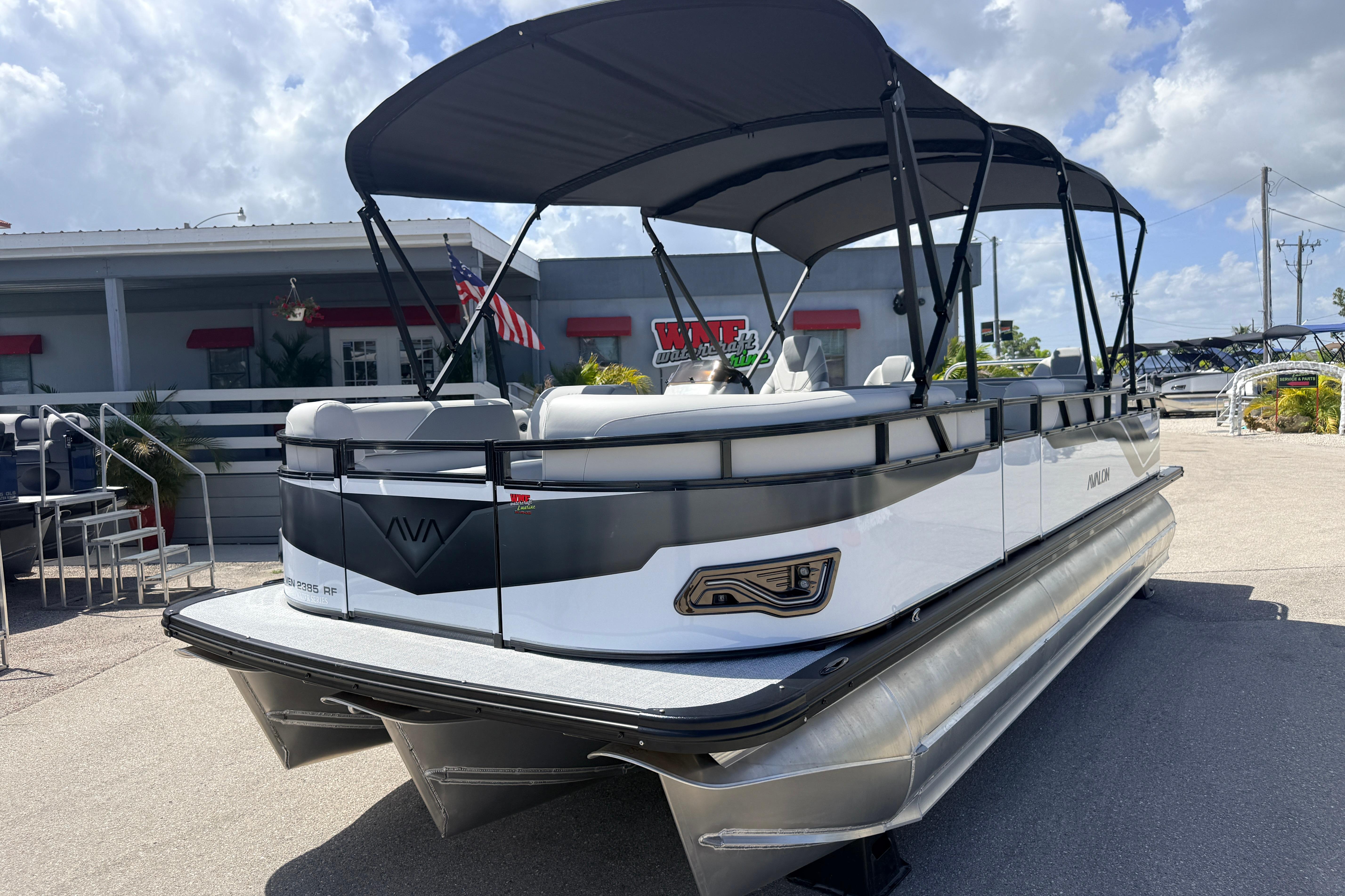 2026 Avalon 2385 Venture 85 Tri Toon boat with canopy, parked outdoors.
