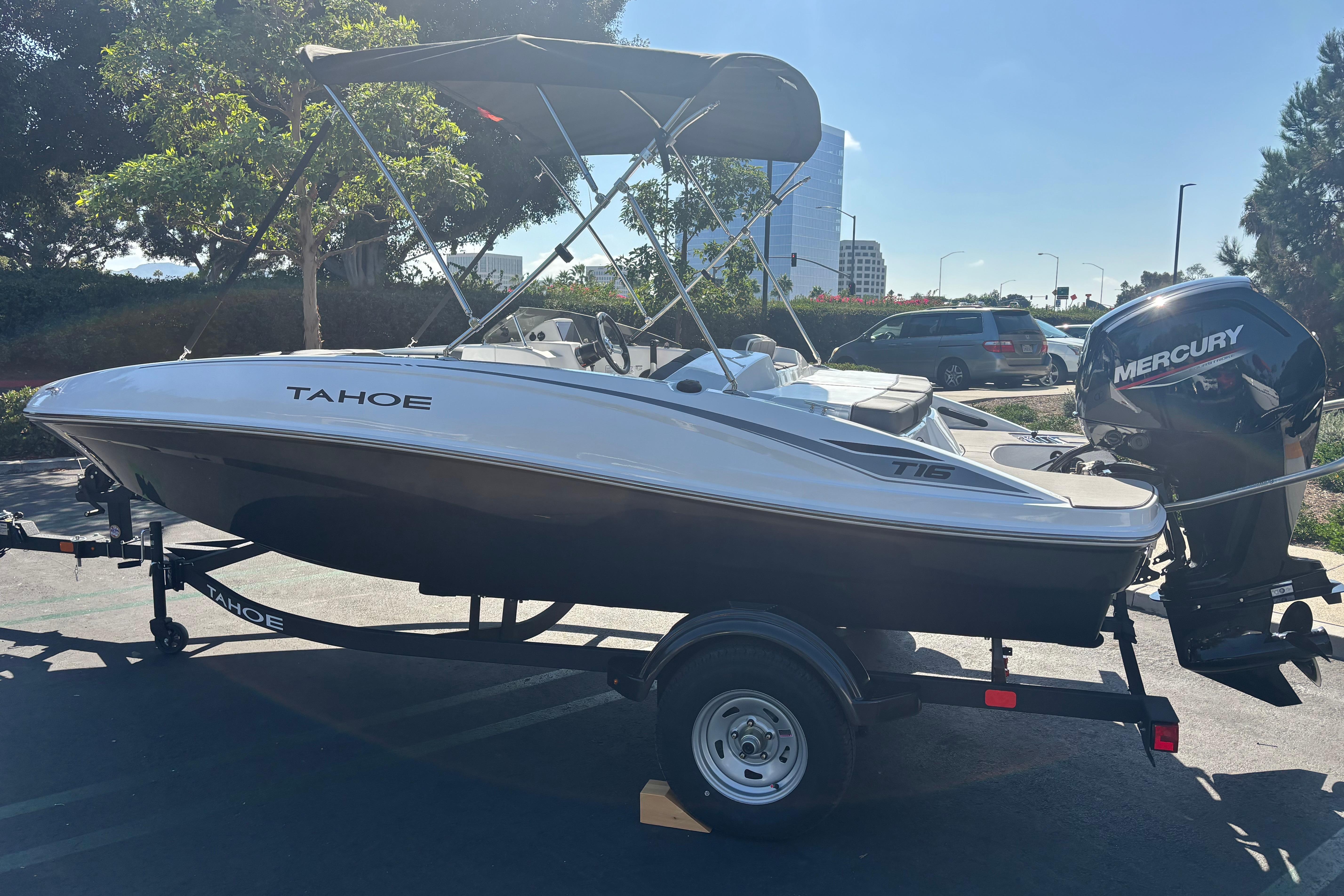 2026 Tahoe T16 boat with Mercury outboard motor on a trailer in a parking lot.