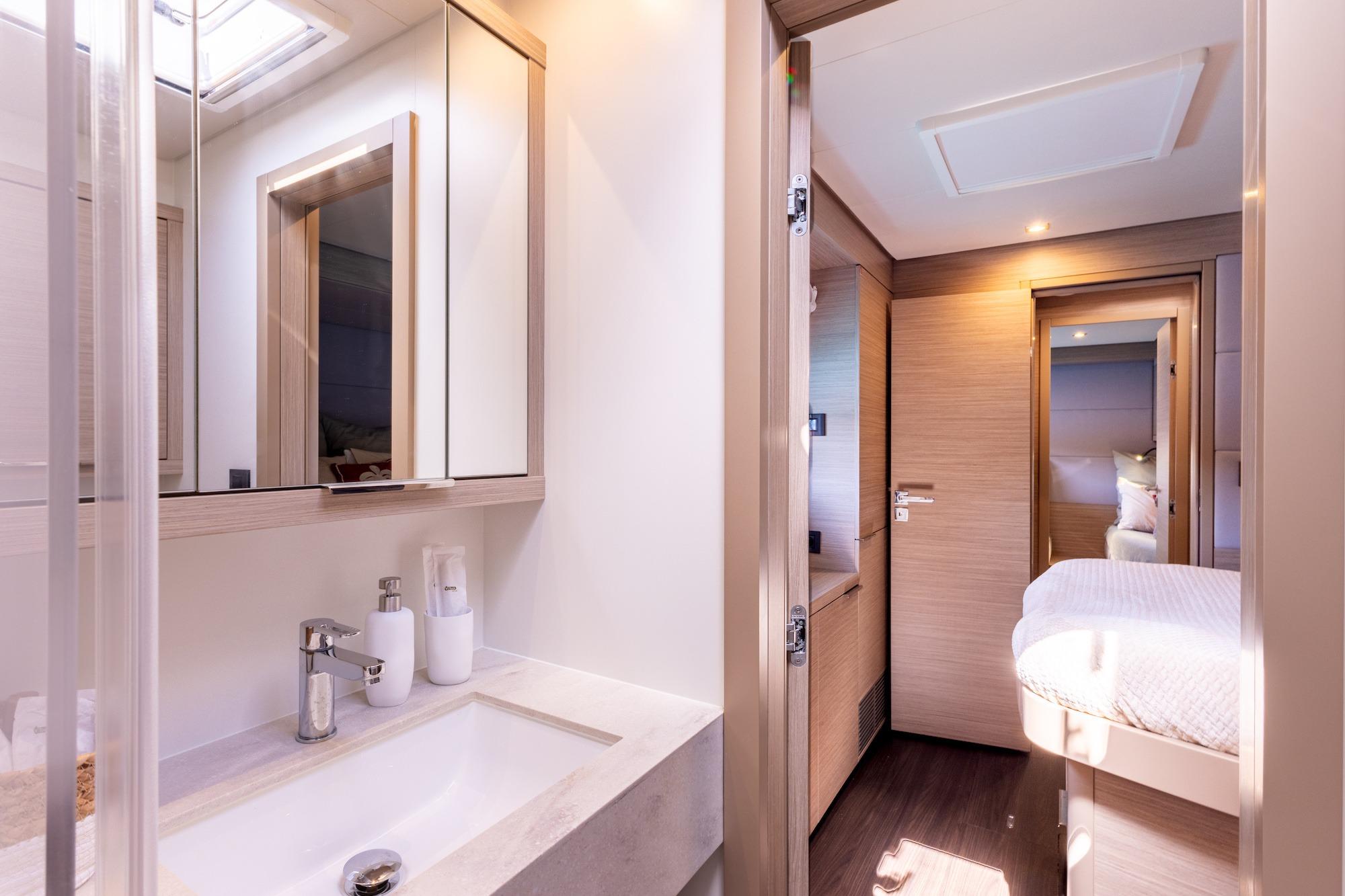 Modern bathroom and bedroom interior on 2023 Lagoon 55 yacht, featuring sleek design and wood accents.