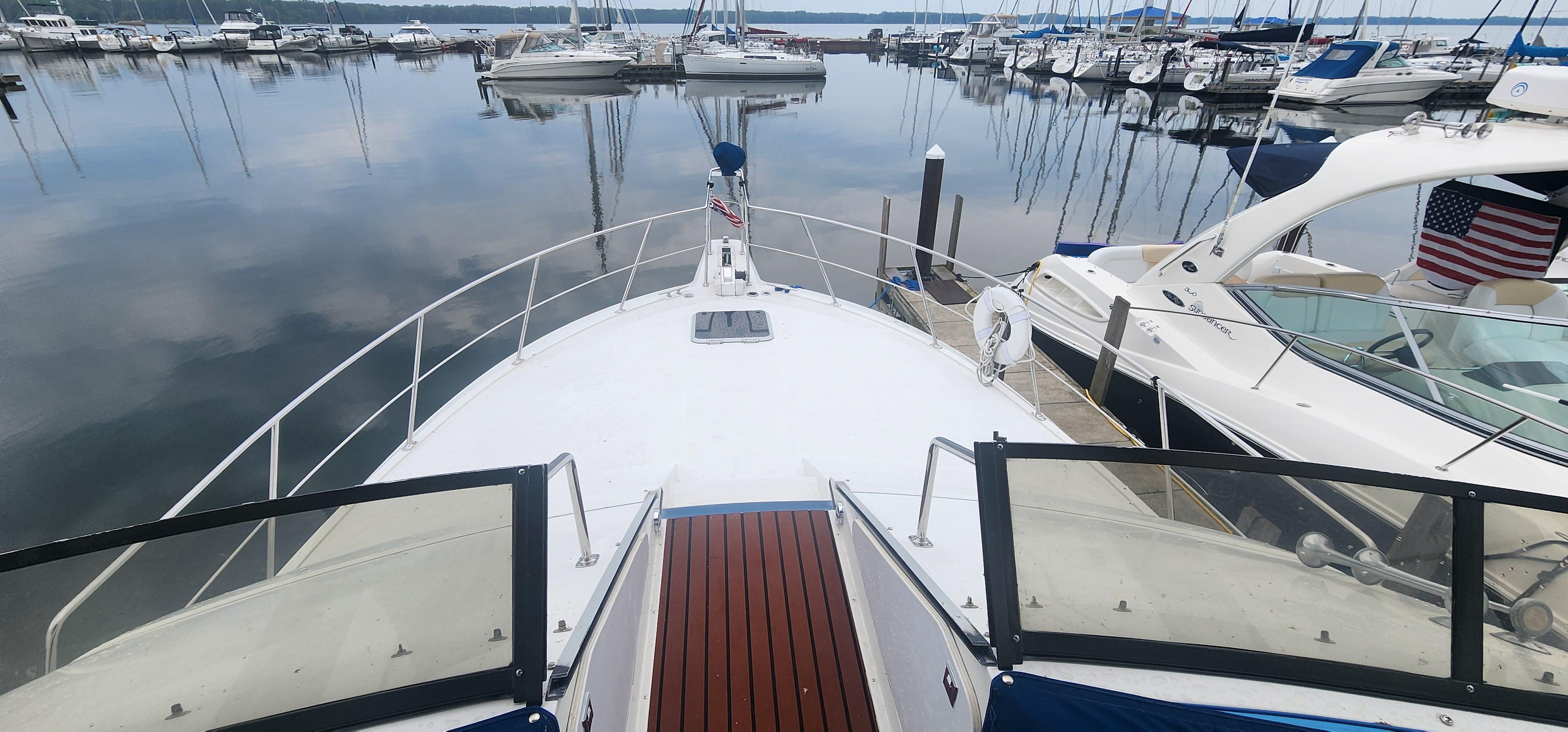 1990 Carver 38 Santego yacht docked at a marina, surrounded by calm water and other boats.