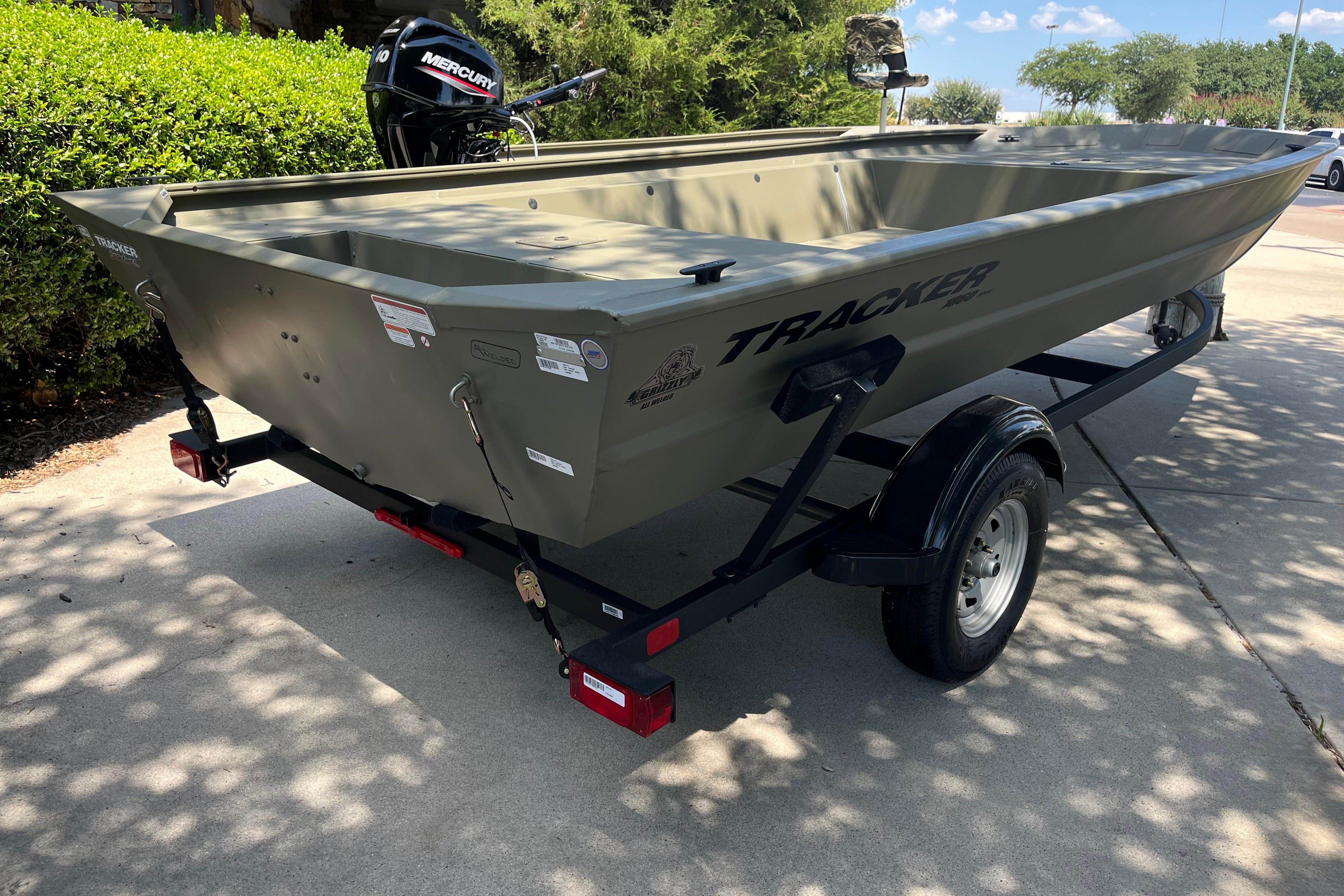 2025 Tracker GRIZZLY 1860 Utility boat on trailer, parked outdoors.