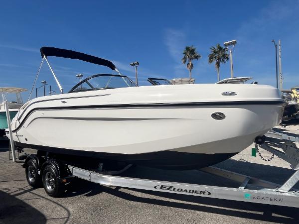 2021 Bayliner DX 2200 boat on trailer, displayed outdoors under clear blue sky.