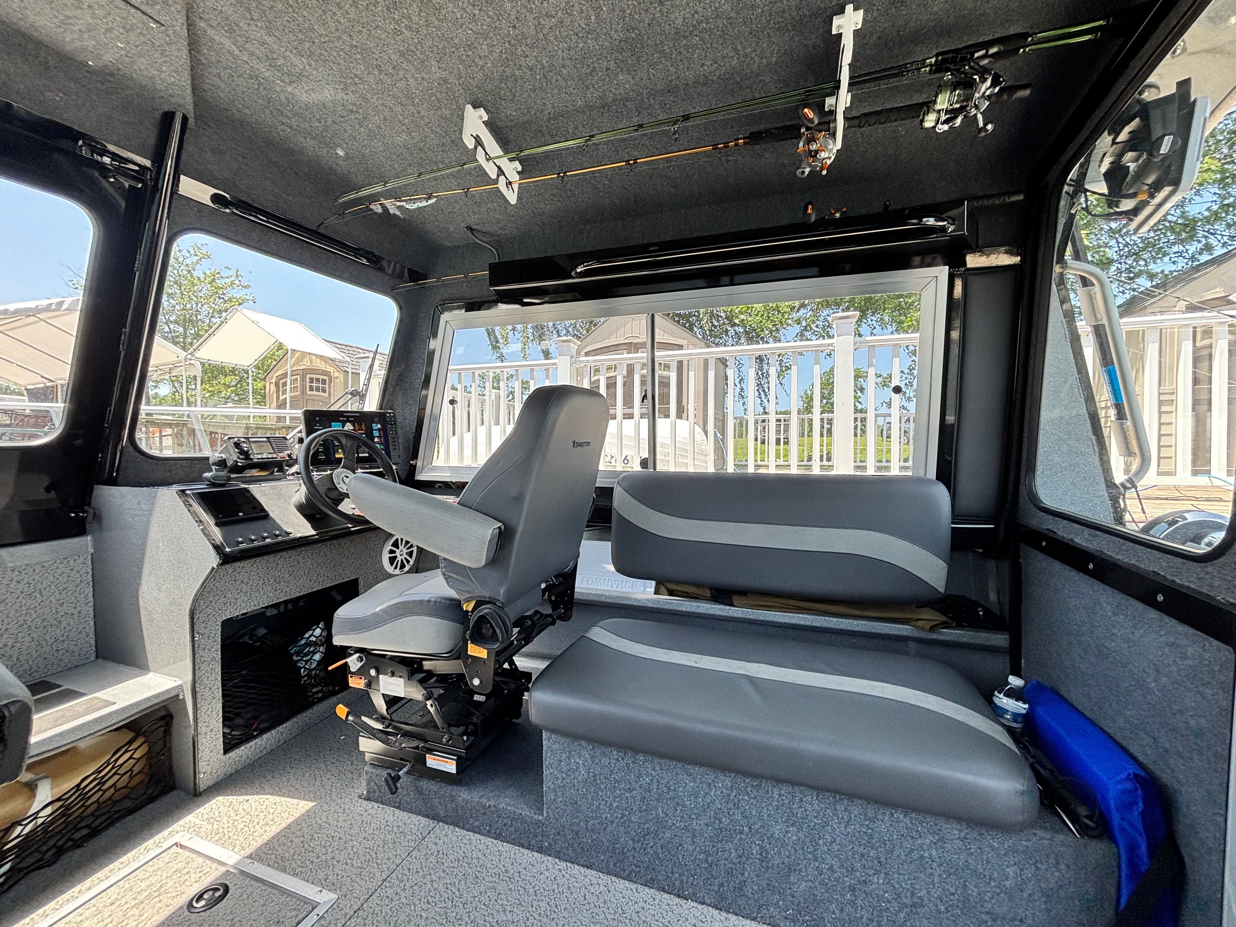 Interior of a 2021 Spartan 240 Maximus boat with gray seating and fishing rods.