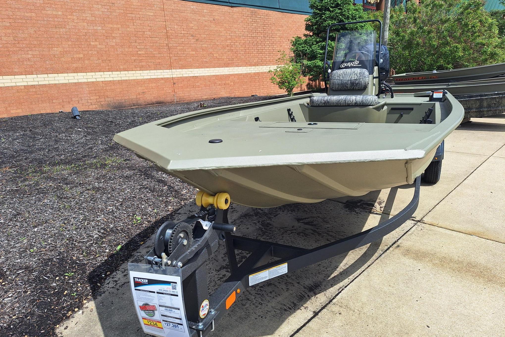2026 Tracker Grizzly 1860 CC boat on trailer, displayed outdoors near a brick wall.