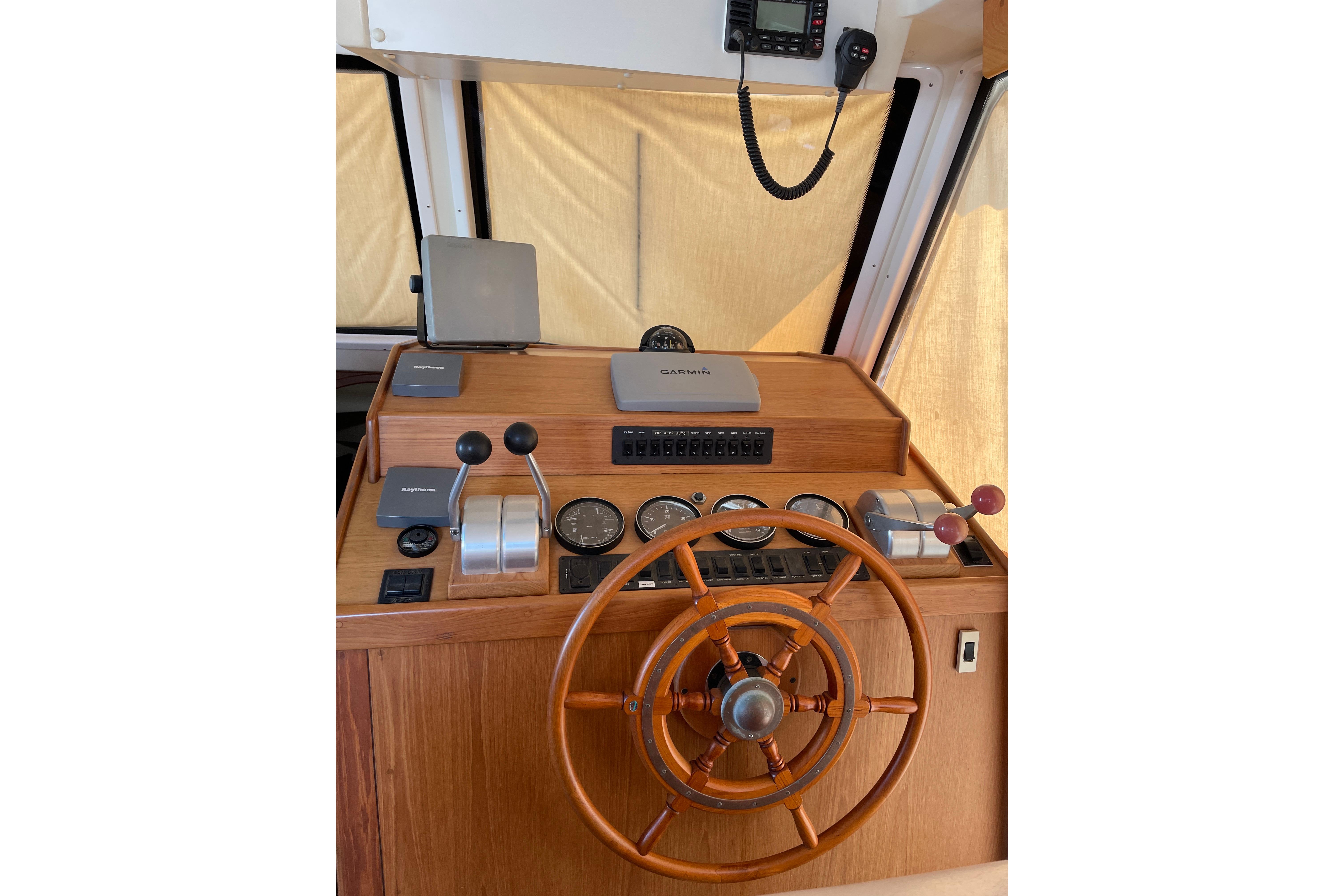 1999 Mainship 430 Trawler helm with wooden wheel and navigation instruments.