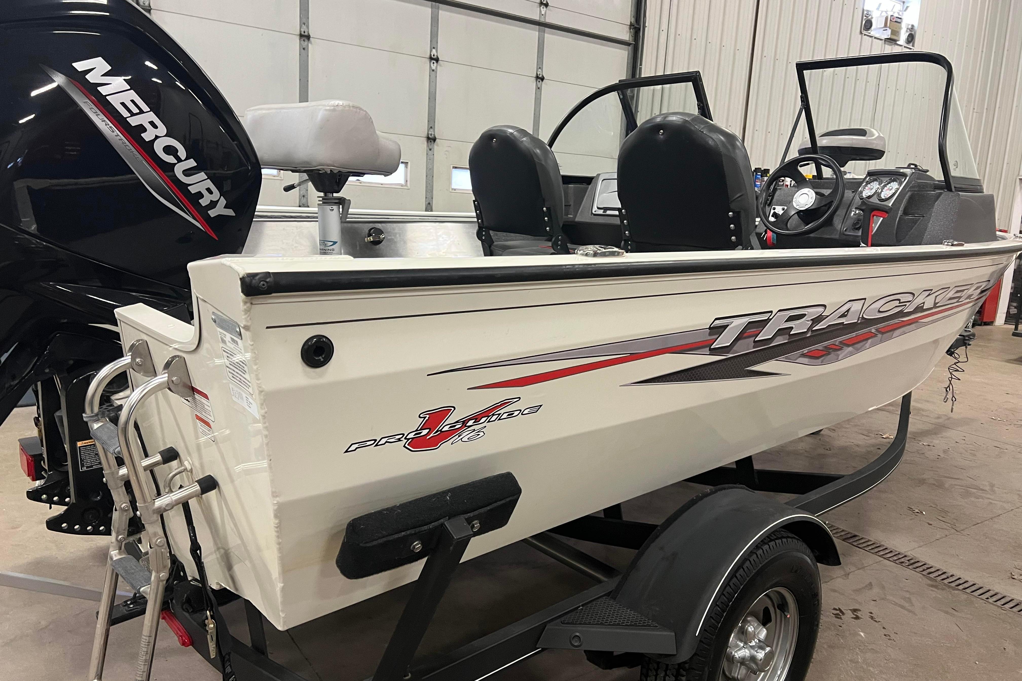 2022 Tracker Pro Guide V-16 WT boat with Mercury engine in a garage.