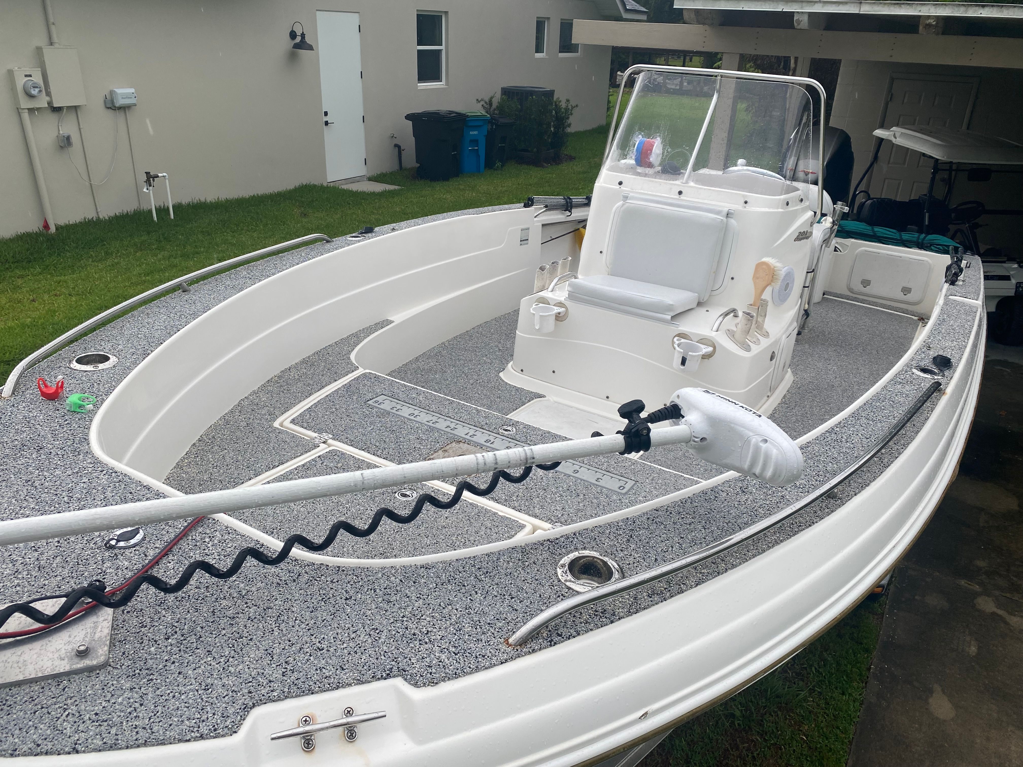 A 2003 Aquasport 201 Osprey with open deck and helm console, parked on a lawn.