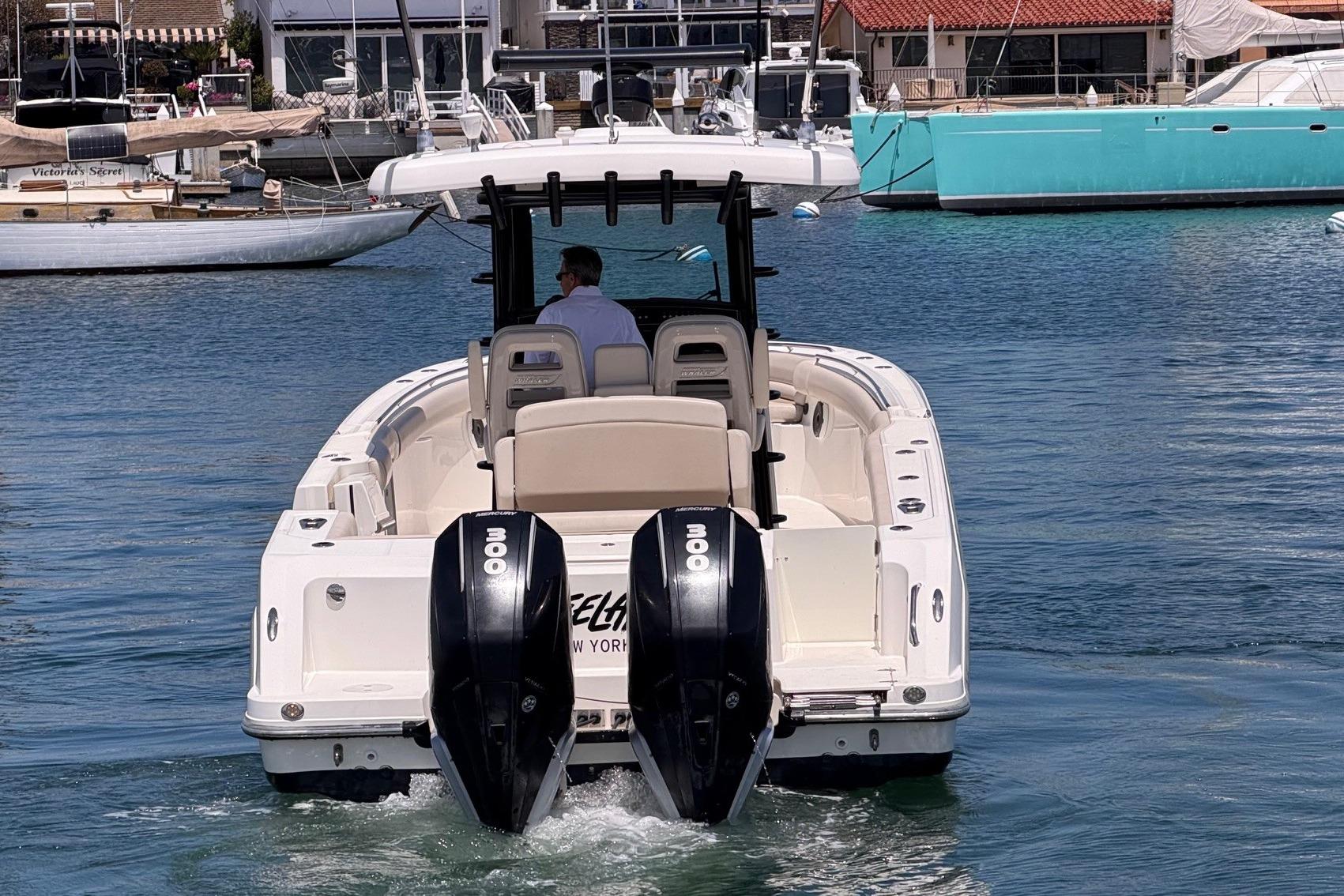 2021 Boston Whaler 330 Outrage boat with dual engines in a marina setting.