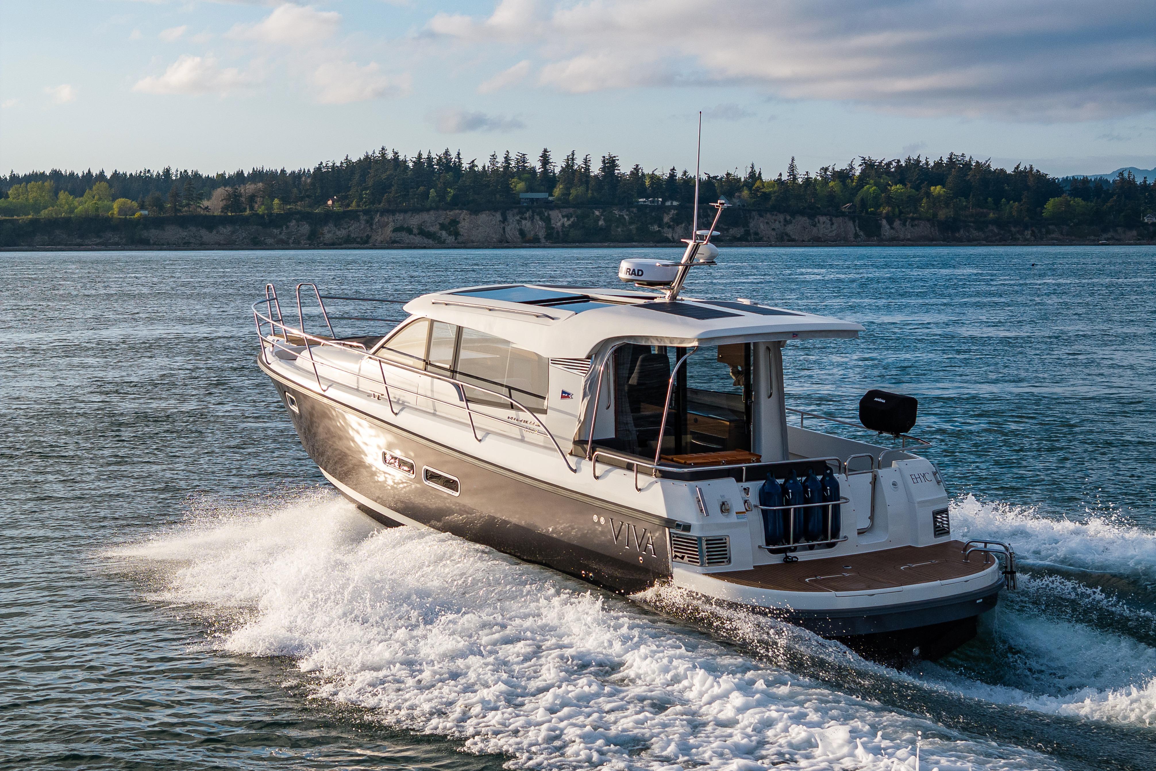 2022 Nimbus 365 Coupe cruising on a scenic waterway with lush green shoreline.