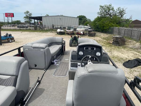 2023 Regency 250DL3 pontoon boat with gray seating, parked outdoors.