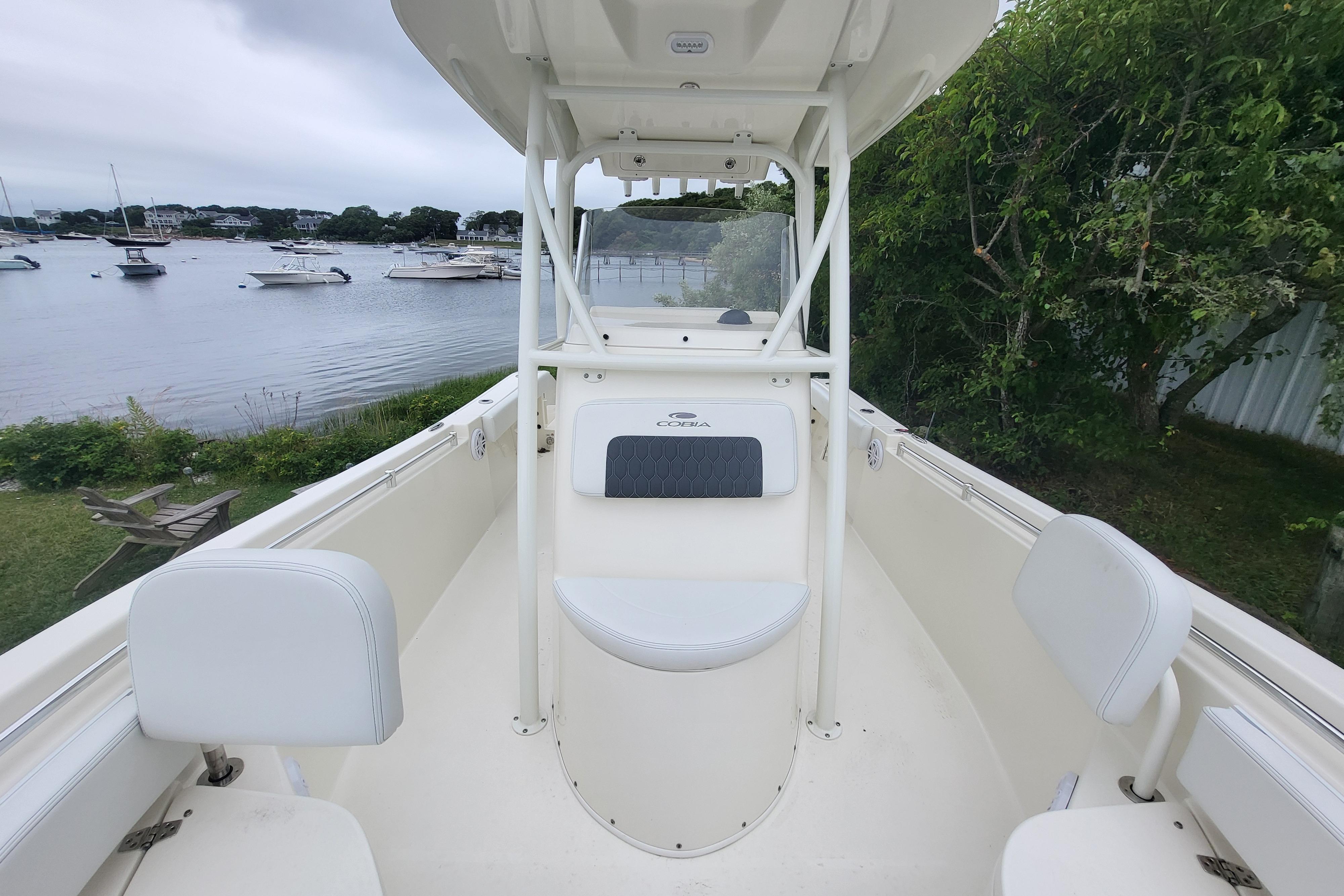 2025 Cobia 220 Center Console boat docked by a scenic waterfront.