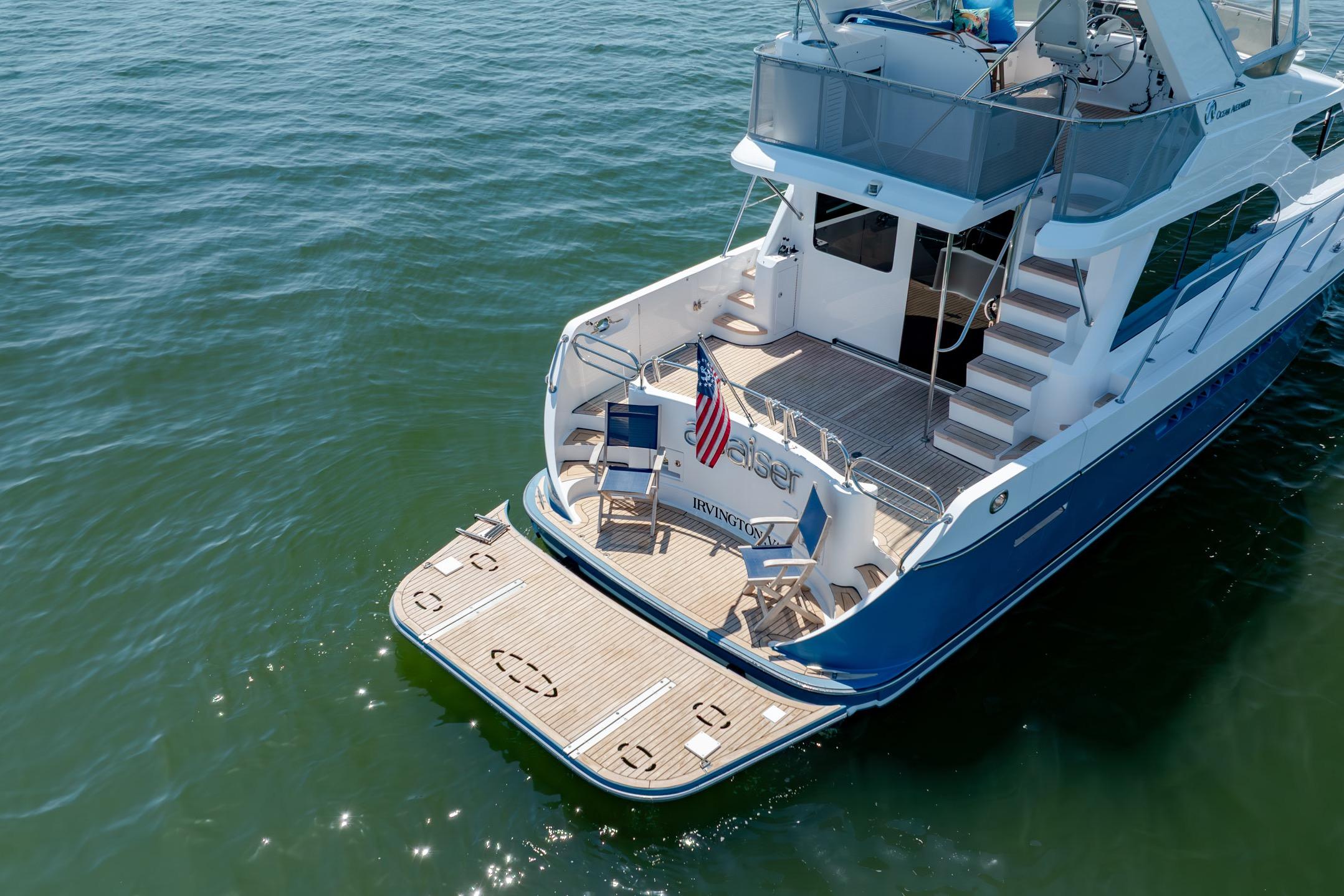 Ocean Alexander yacht with deck chairs and American flag on calm water.
