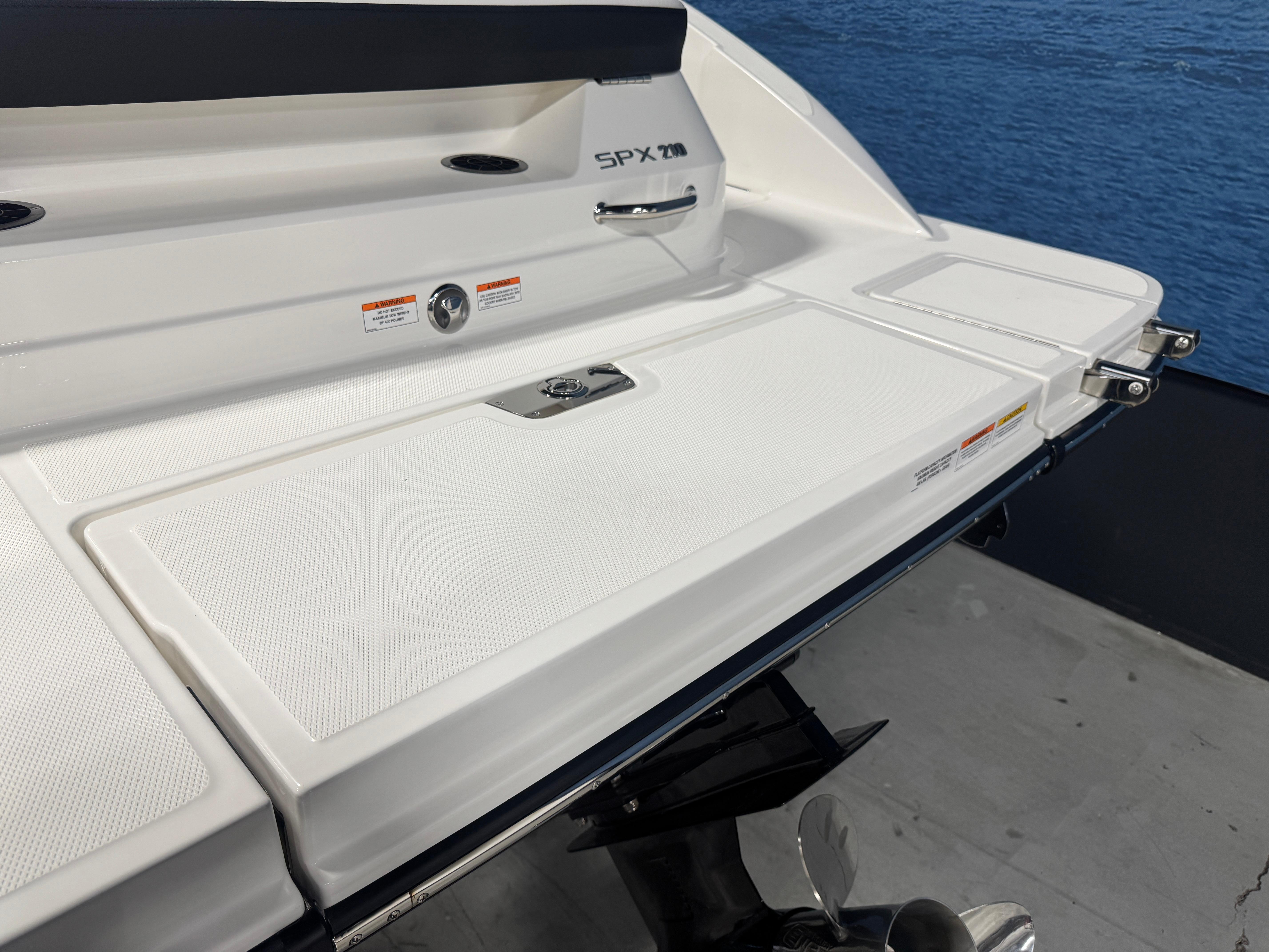 2026 Sea Ray SPX 210 boat stern with swim platform and propeller, docked by the water.