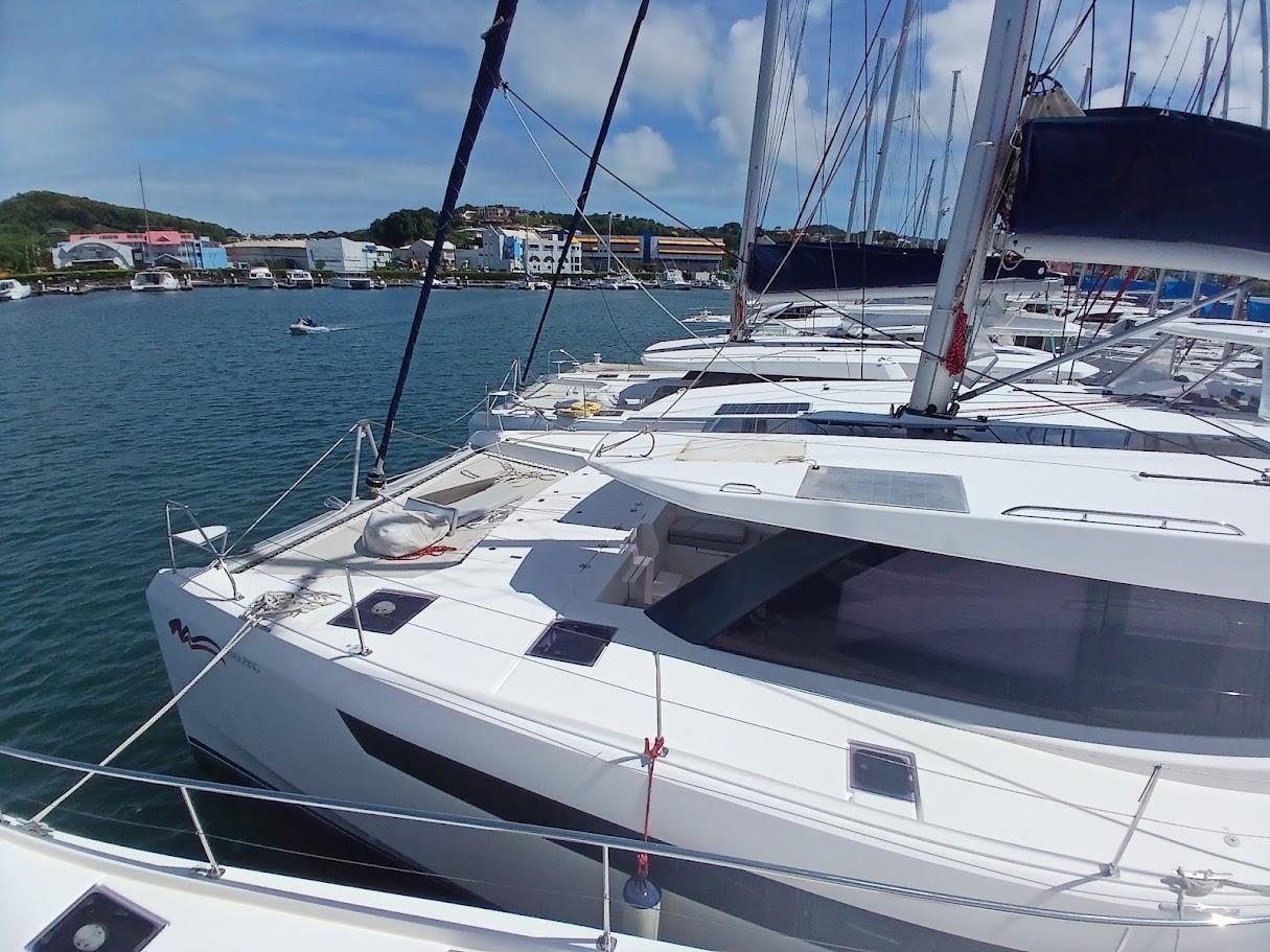 Modern Leopard 50 catamaran docked in a marina, 2020 model, under clear blue skies.