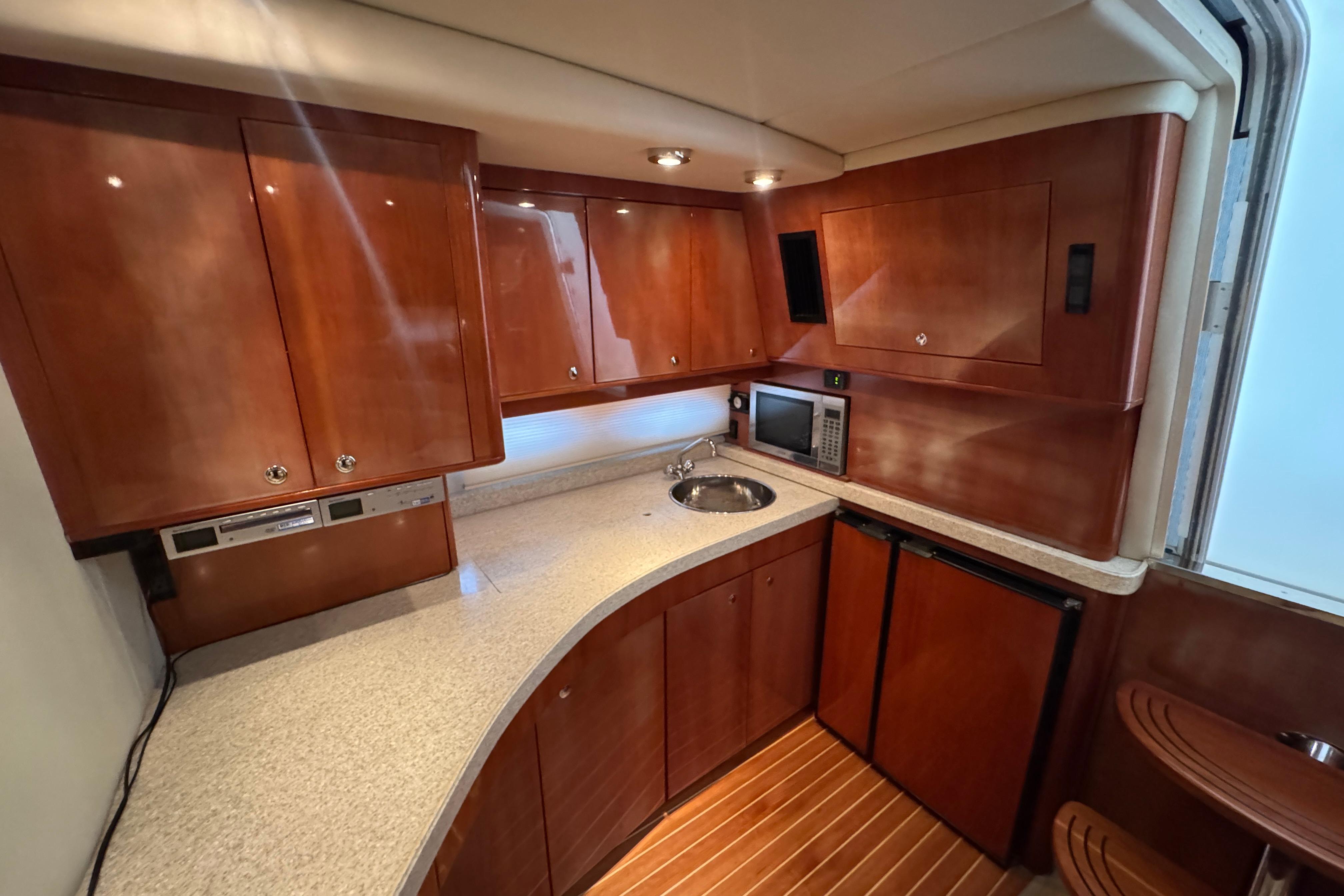 Luxurious 2005 Regal Commodore 4260 yacht kitchen with wood cabinetry and modern appliances.