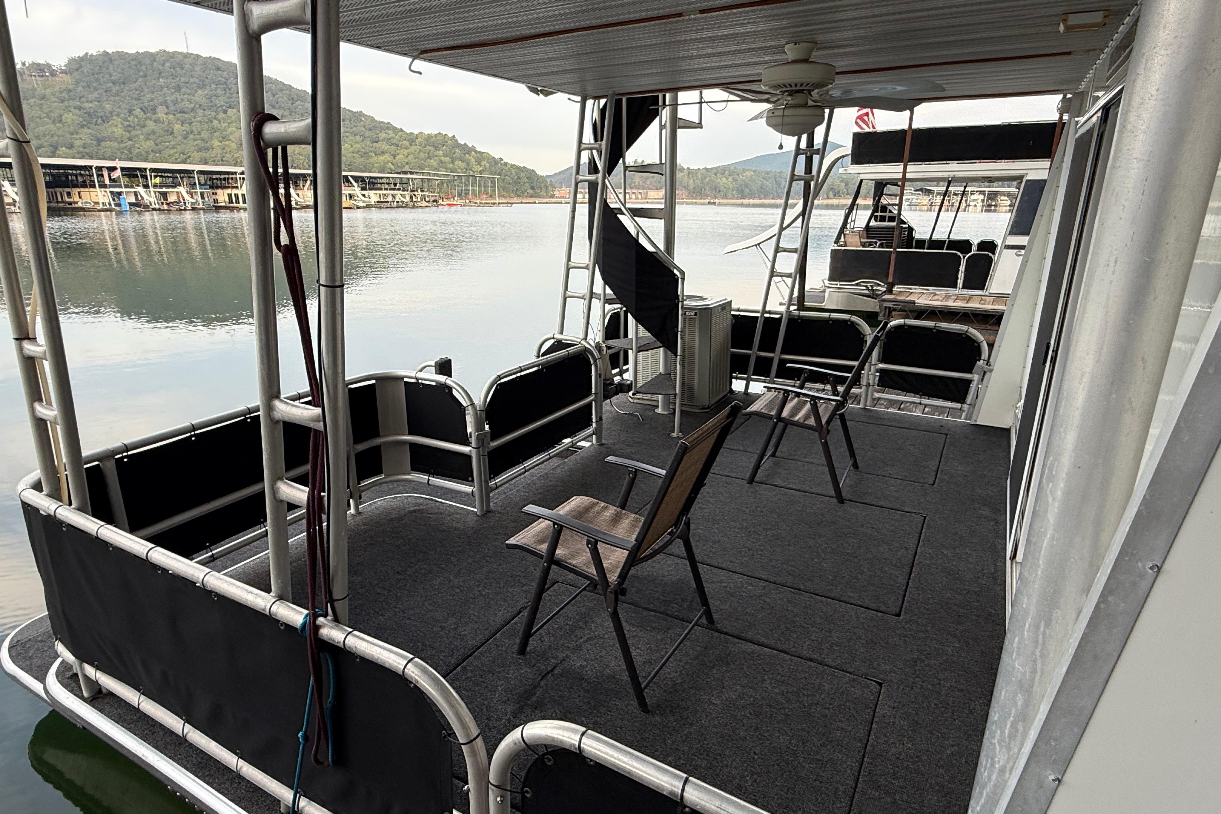 1998 Sumerset 16x76 houseboat deck with chairs, overlooking serene lake and marina.