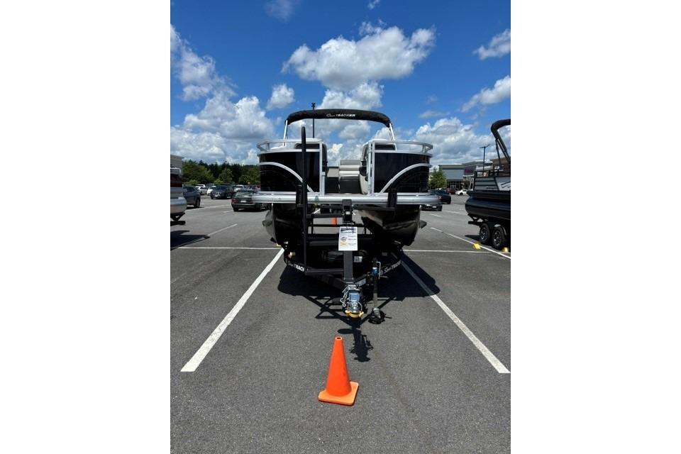 2026 Sun Tracker Fishin' Barge 20 DLX pontoon boat in parking lot under blue sky.