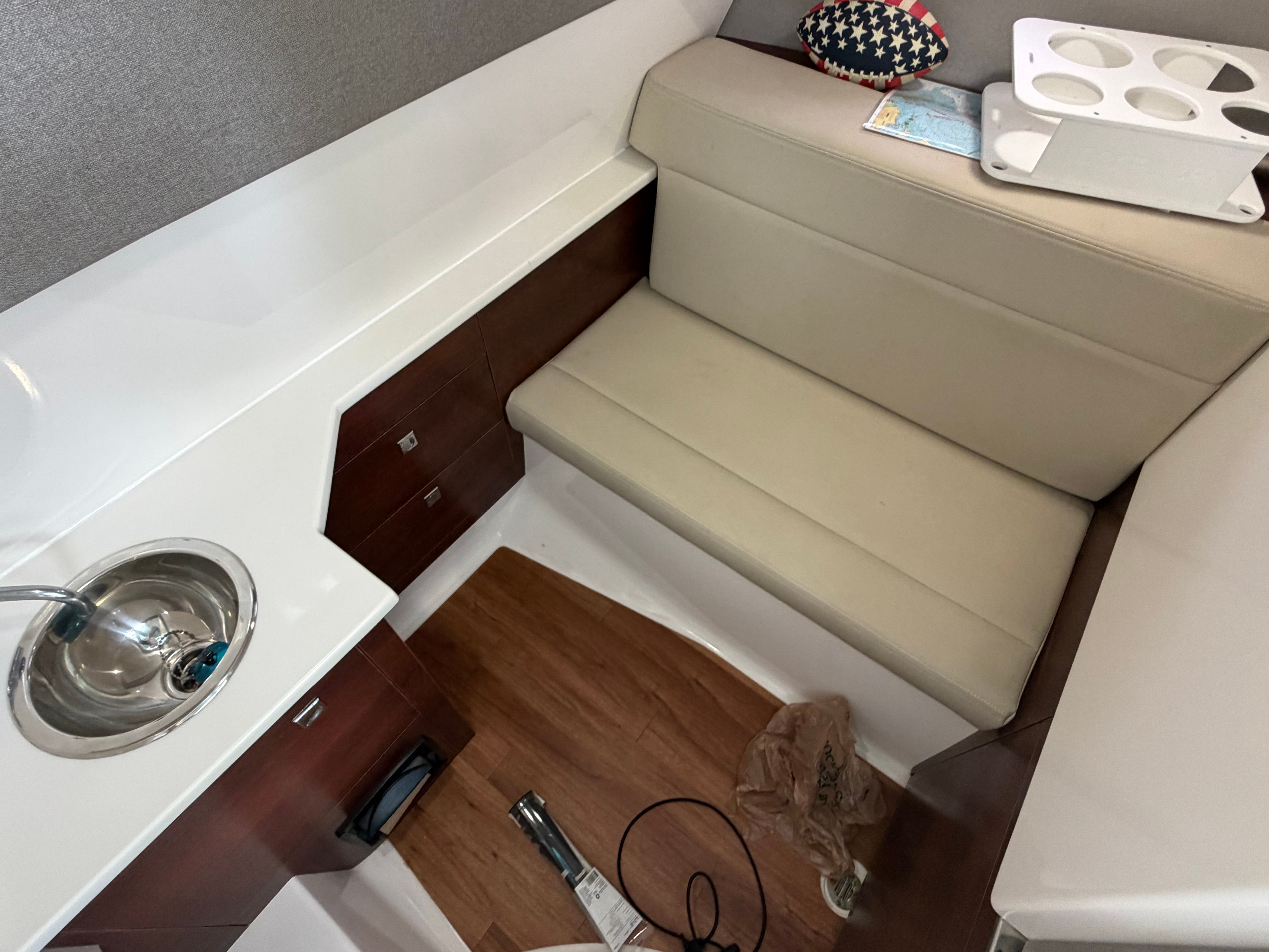 Interior of a modern yacht with seating, sink, and wooden flooring.