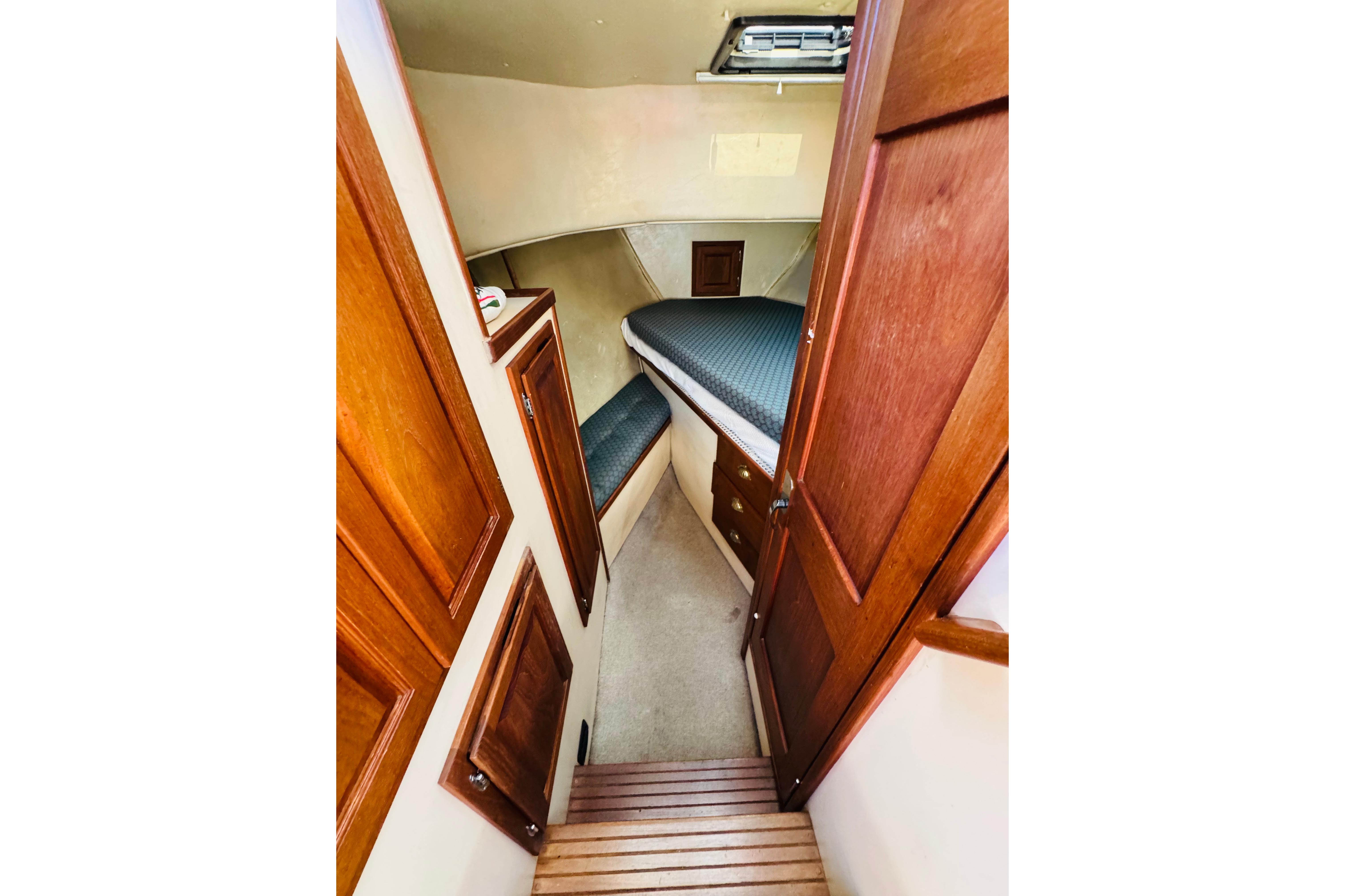 Interior cabin of a 1996 Nordic Tug 32, featuring wooden cabinetry and a cozy sleeping area.