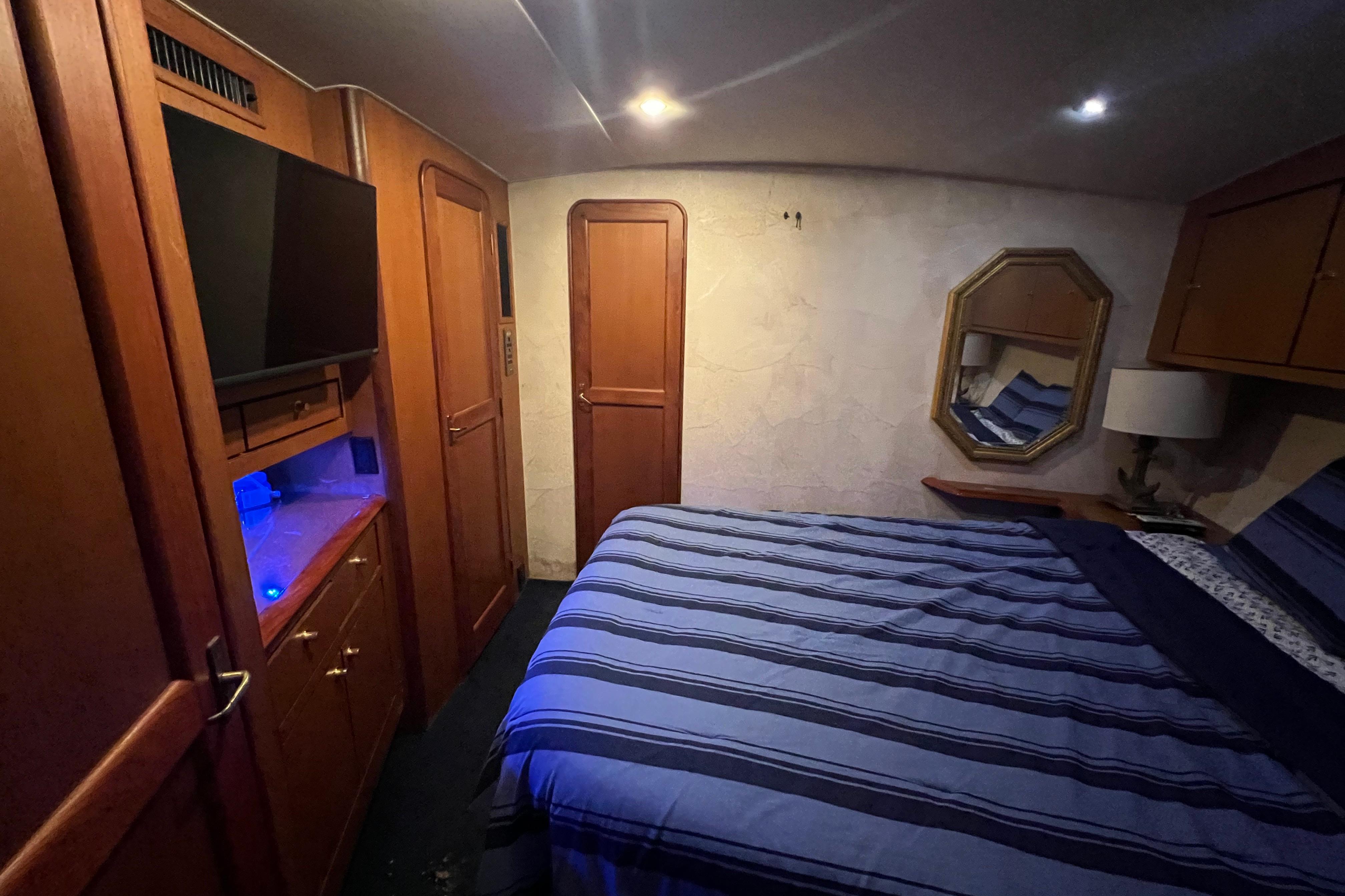 Luxurious bedroom interior of 1999 Ocean Yachts 56 Super Sport with striped bedding and wooden cabinetry.