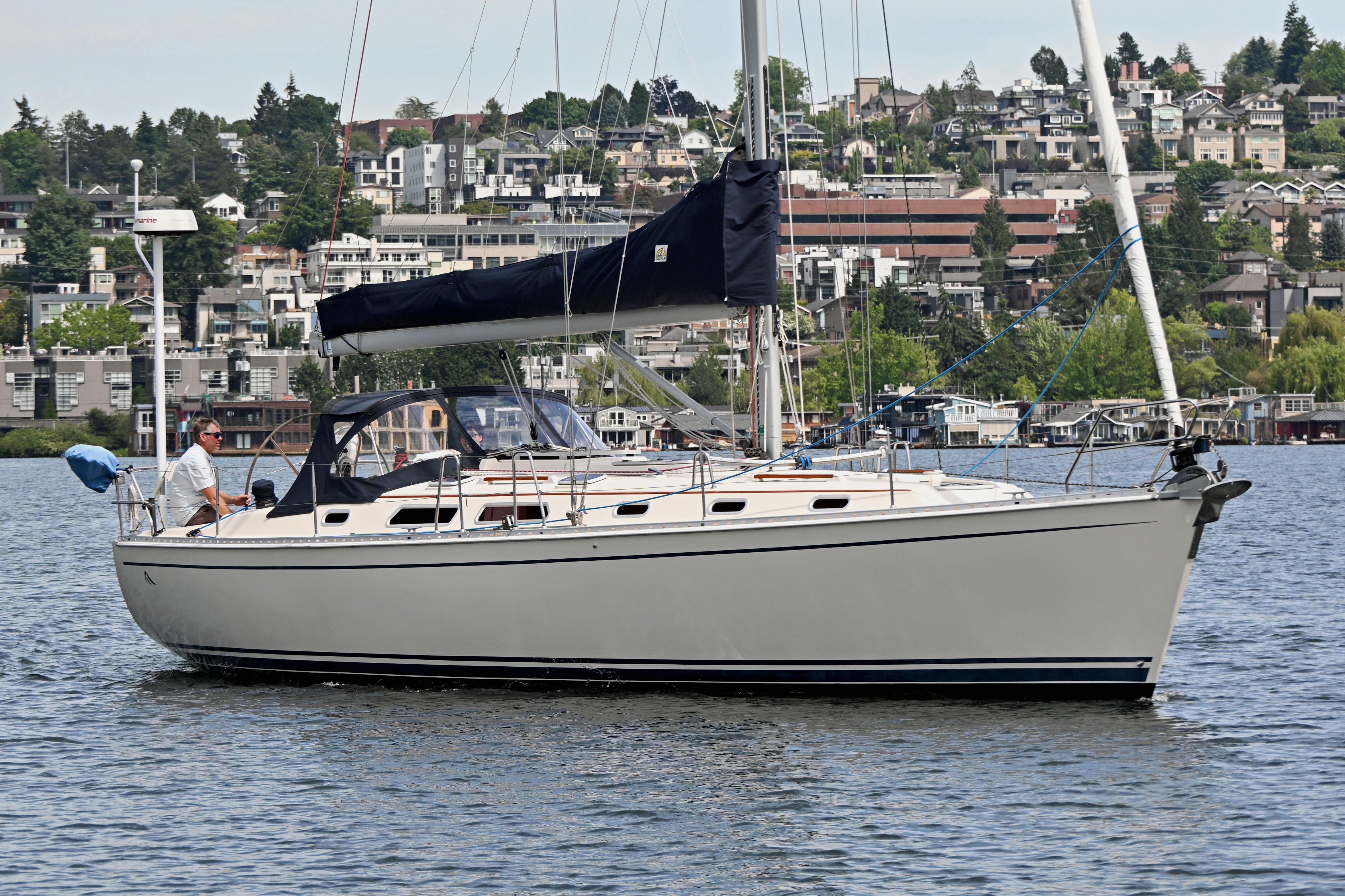 Sailing yacht Hanse 411 from 2004 on a calm lake with a scenic urban backdrop.