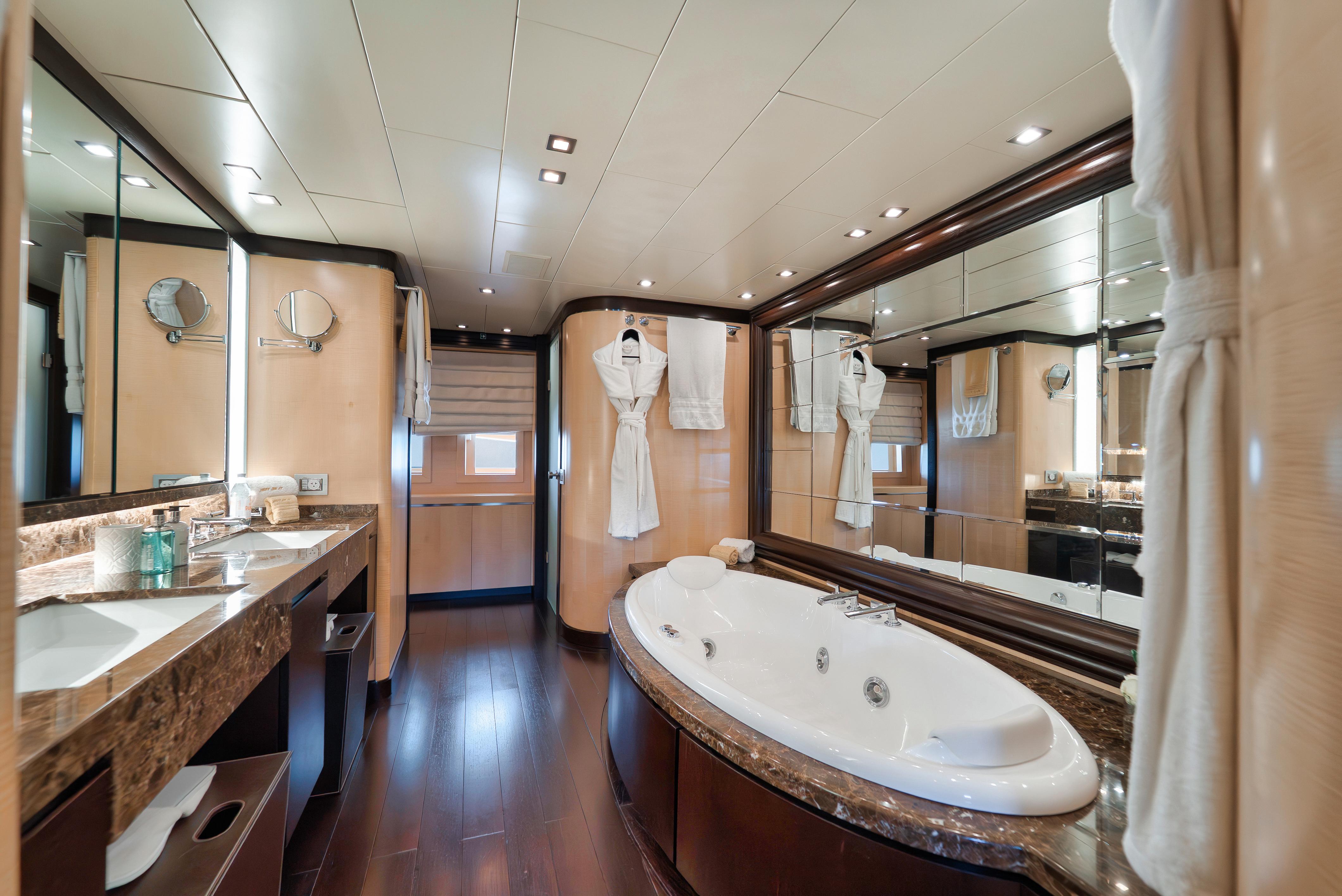 Luxurious yacht bathroom with jacuzzi, marble countertops, and elegant wood flooring on Arno Leopard 46.